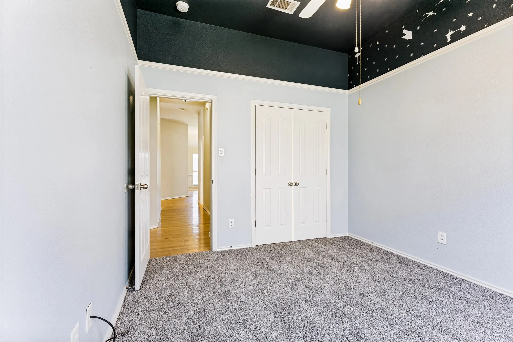 Spacious room featuring gray carpet, light blue walls, and a recessed ceiling with a black finish