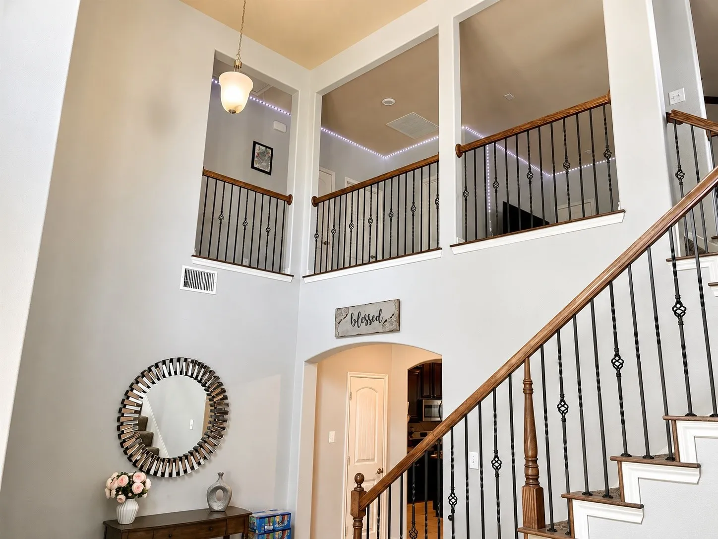 Two-story foyer featuring a grand staircase with wood-finish handrails and wrought iron balusters