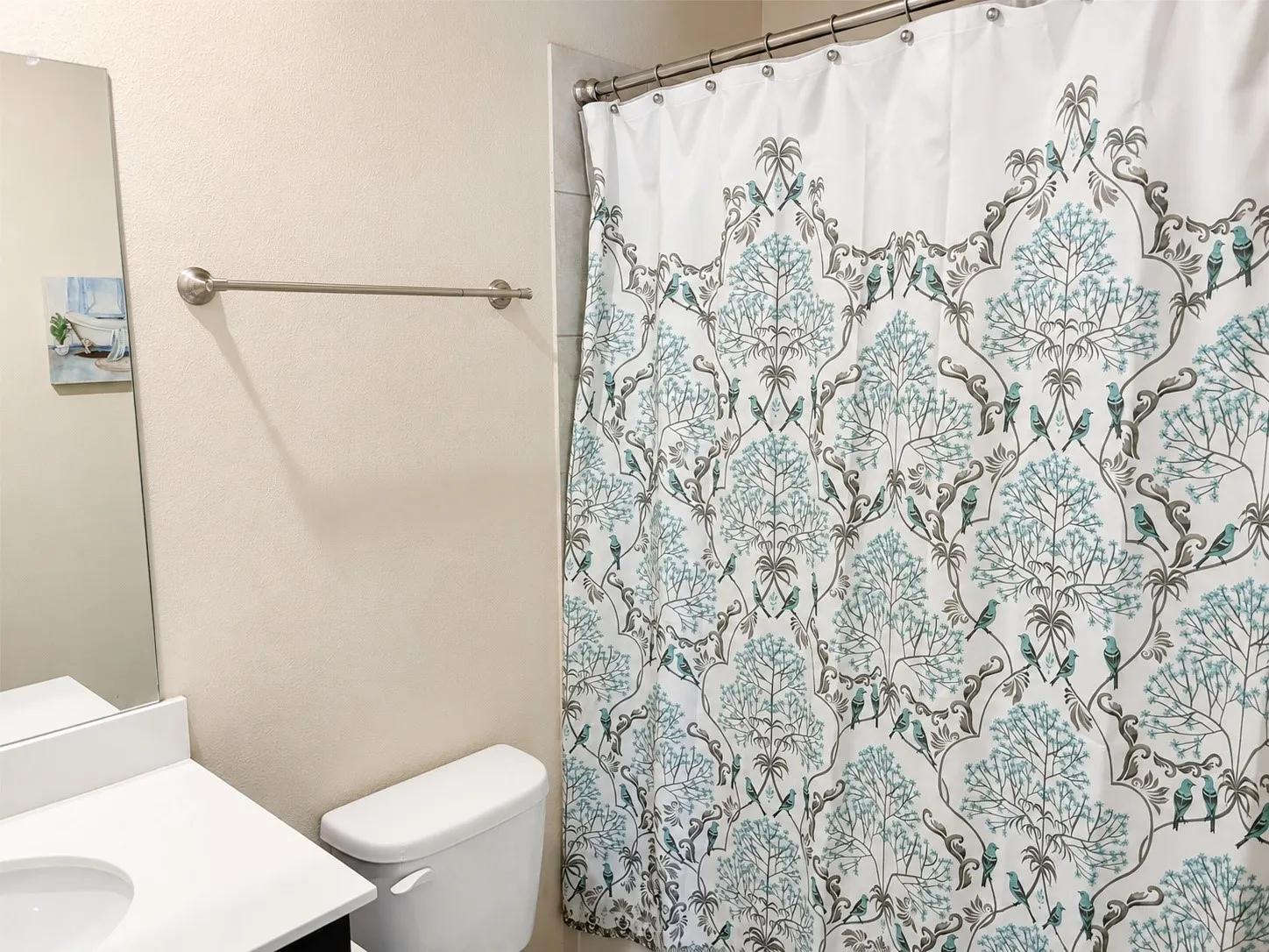 Bathroom featuring a white vanity with an integrated sink, a rectangular mirror, and a toilet