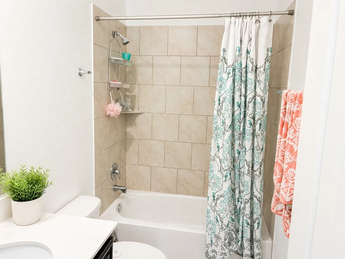 Bathtub with subway-style tiled surround, chrome showerhead, and integrated soap shelf