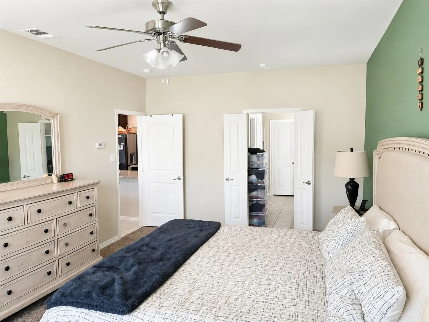 Bedroom featuring a ceiling fan with integrated lighting, a painted accent wall, and wood-finish flooring