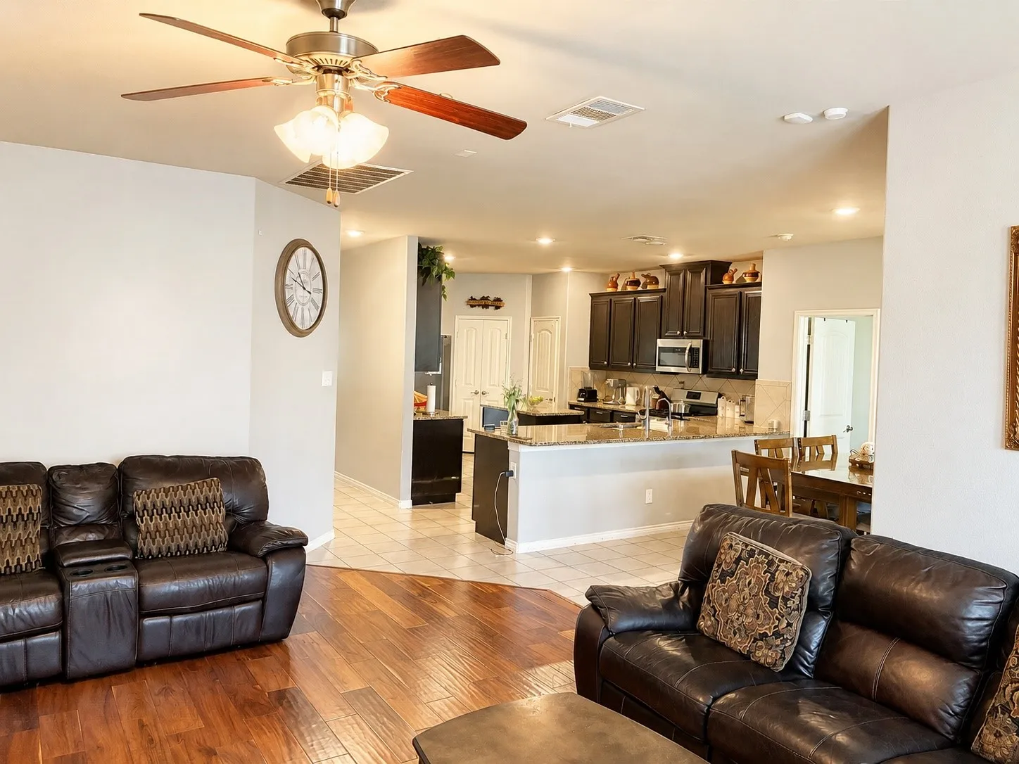 Open-concept living area featuring wood-finish flooring, a ceiling fan with integrated lighting, and recessed lighting