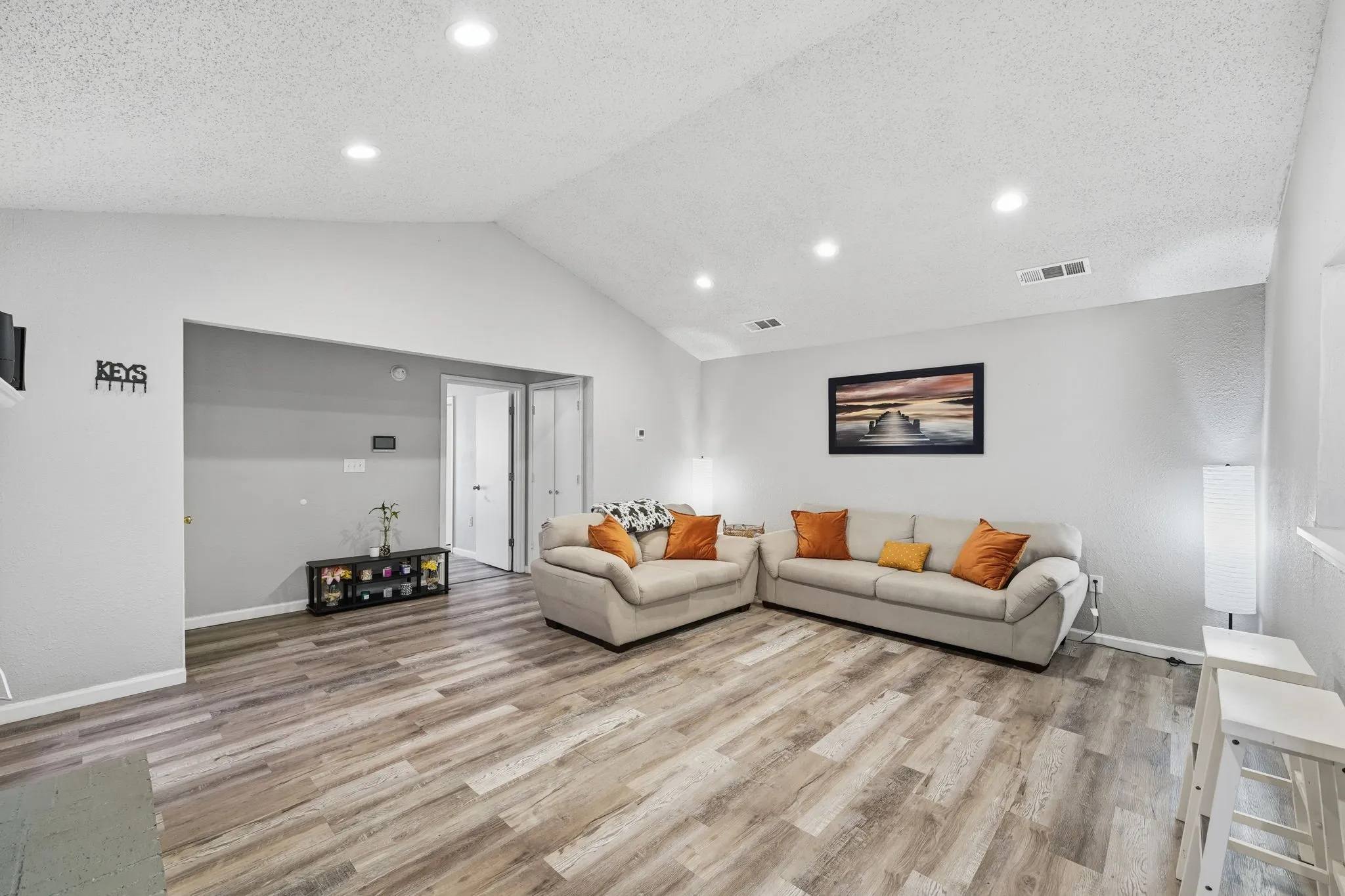 Spacious living area with vaulted ceilings, updated flooring, and an open, airy feel.