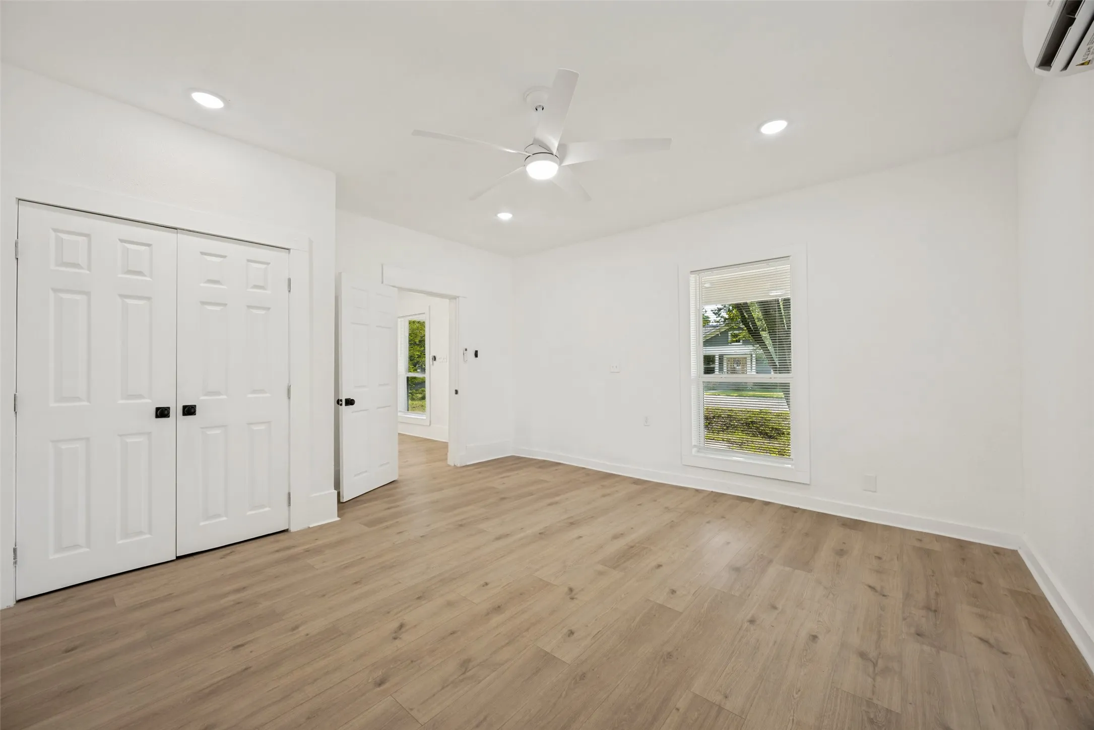 Spacious room featuring wood-finish flooring, recessed lighting, and a ceiling fan