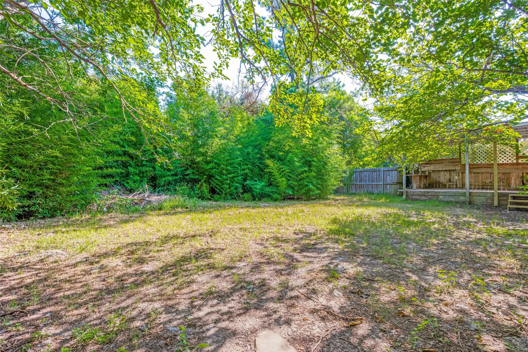 Expansive backyard featuring a large wooden deck, privacy fencing, and mature trees providing natural screening