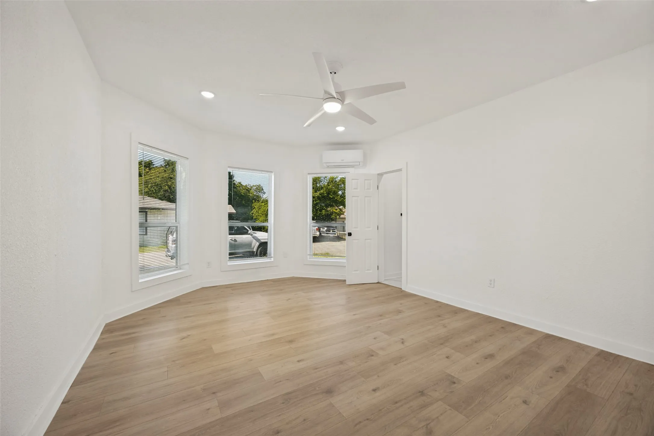 Spacious room featuring light wood-finish flooring, recessed lighting, and a contemporary ceiling fan