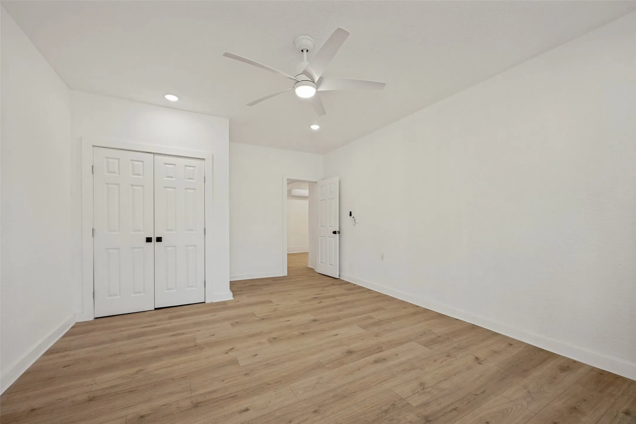 Spacious room featuring wood-finish flooring and a contemporary ceiling fan with integrated lighting