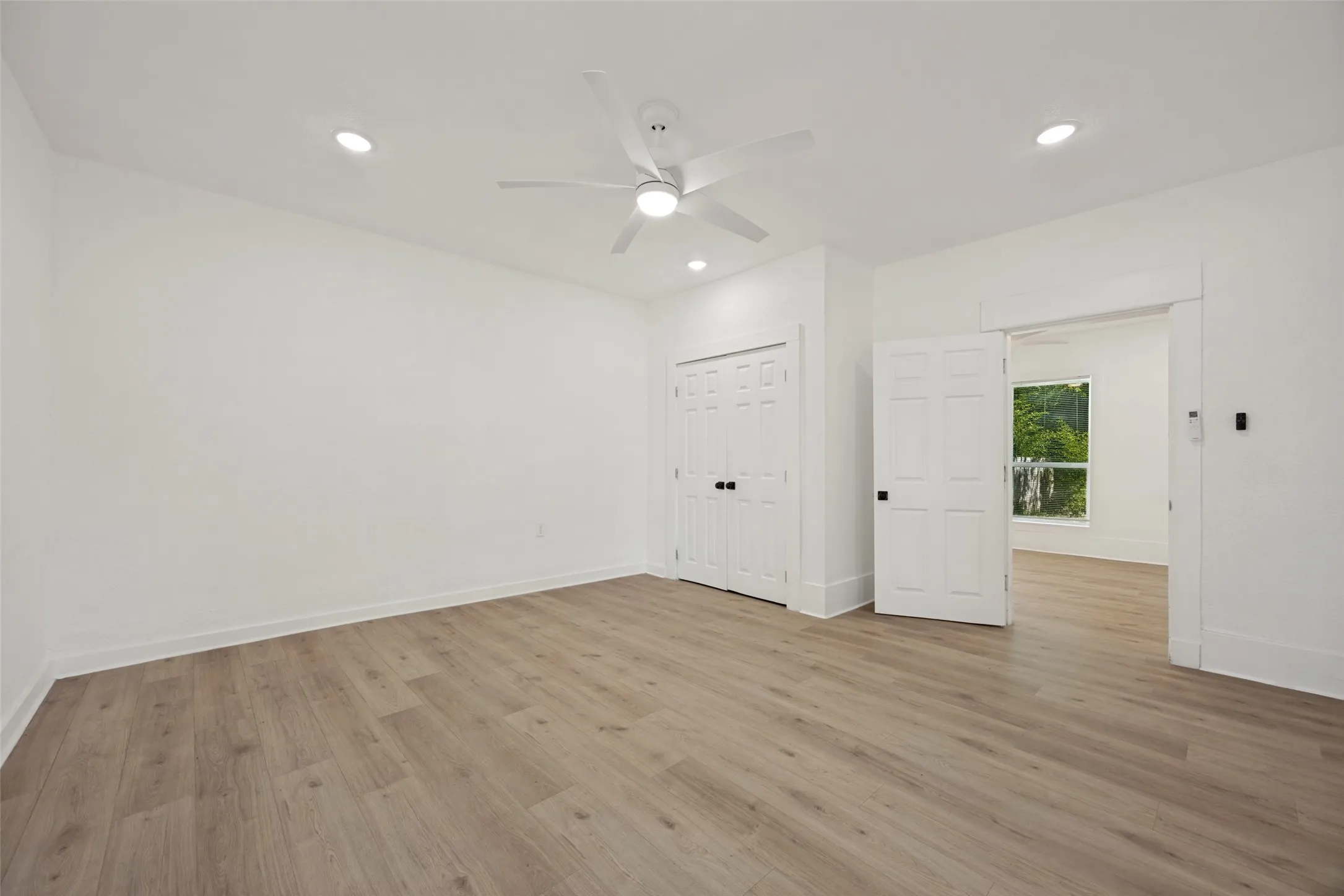 Spacious interior room featuring light wood-finish flooring, recessed lighting, and a ceiling fan