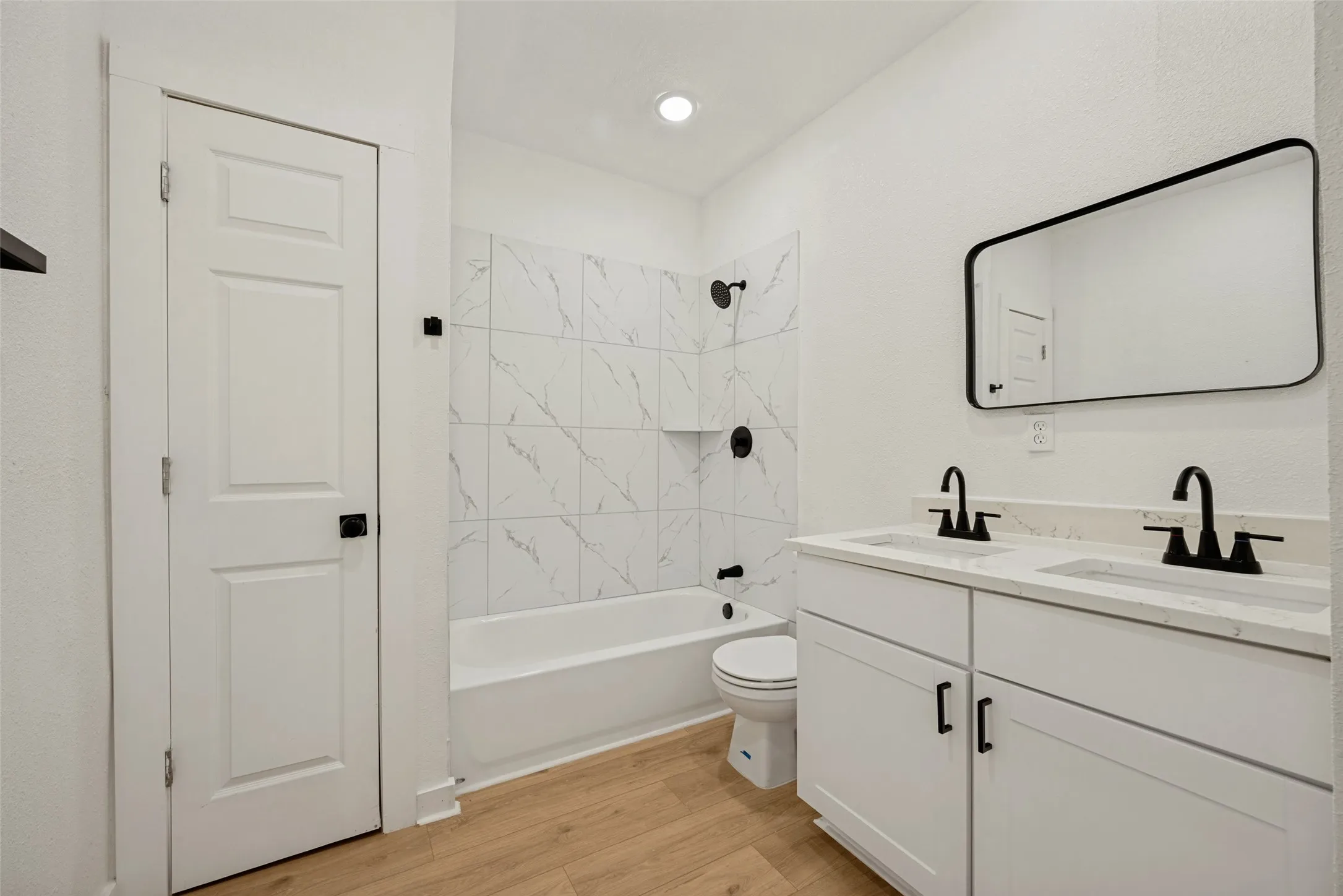 Bathroom featuring a dual vanity with white cabinetry, light-toned countertops, and matte black hardware