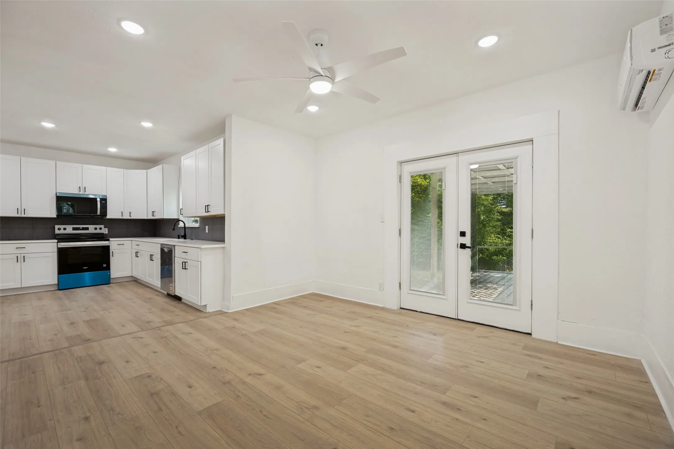 Open-concept living area with wood-finish flooring, recessed lighting, and a ceiling fan