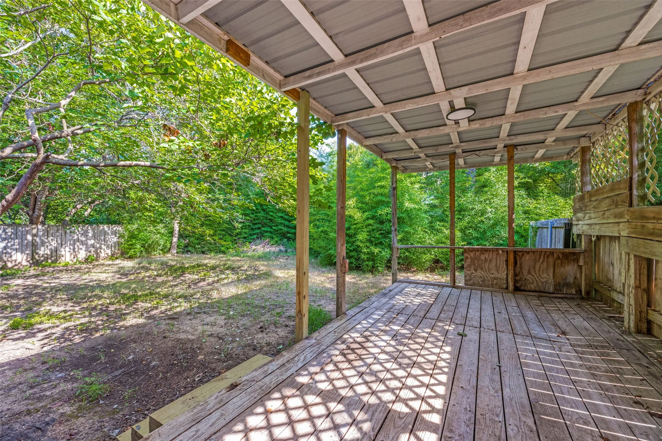 Covered outdoor deck featuring natural wood flooring and a corrugated metal roof