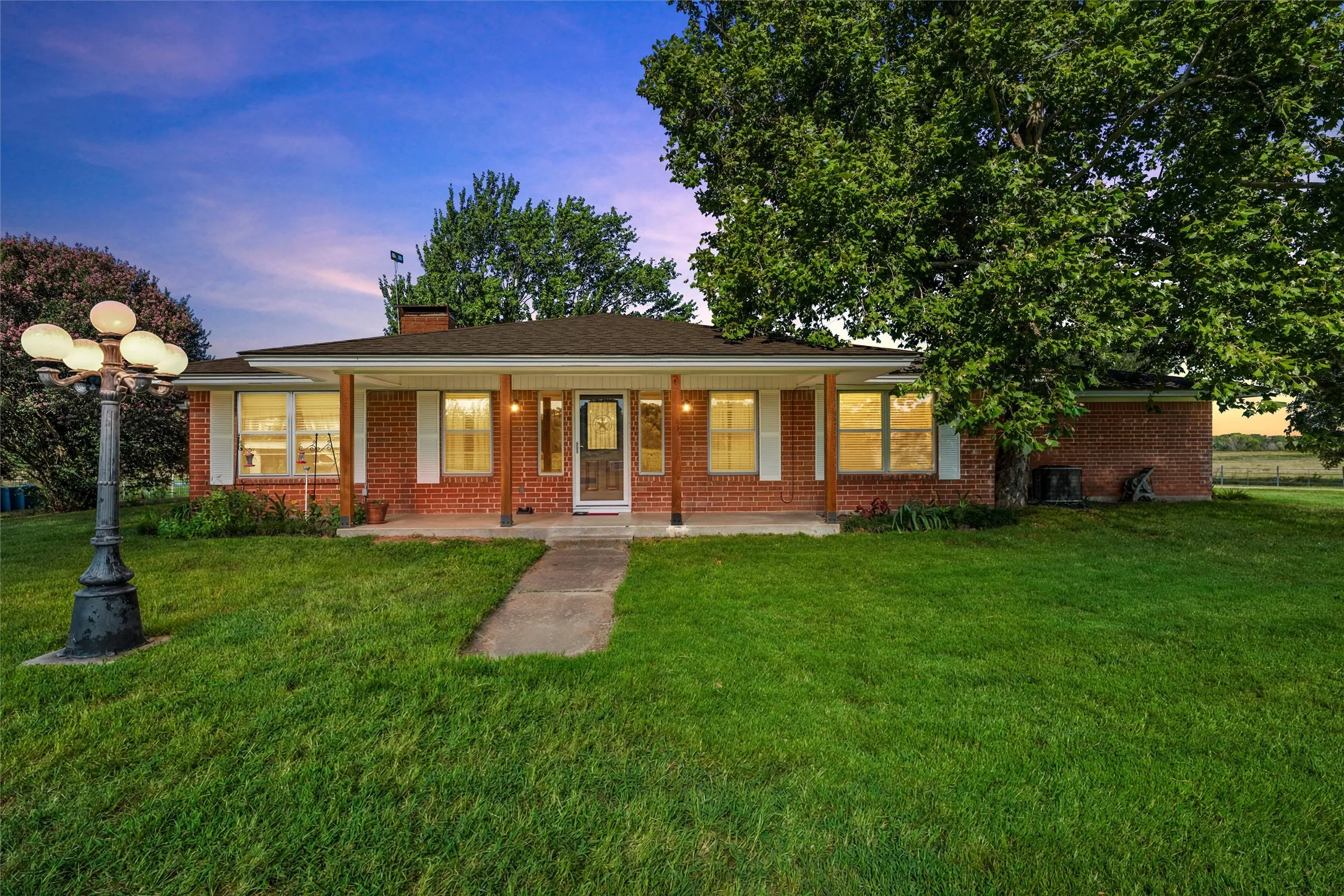 Brick exterior ranch home featuring a covered front porch, white window shutters, and a central sidewalk leading to the main entry