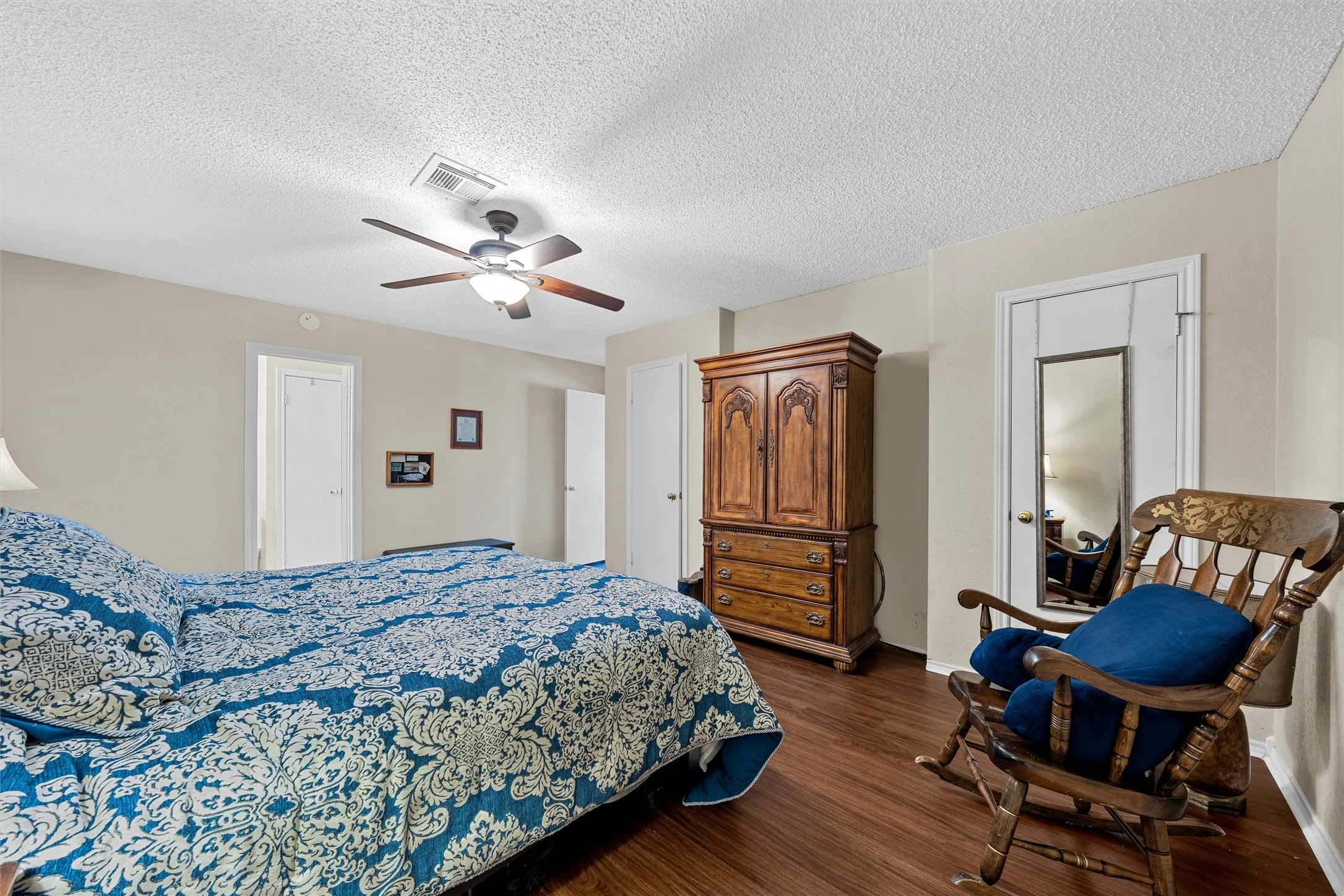 Spacious room featuring wood-finish flooring, light neutral wall tones, a ceiling fan with integrated lighting, and white trim work
