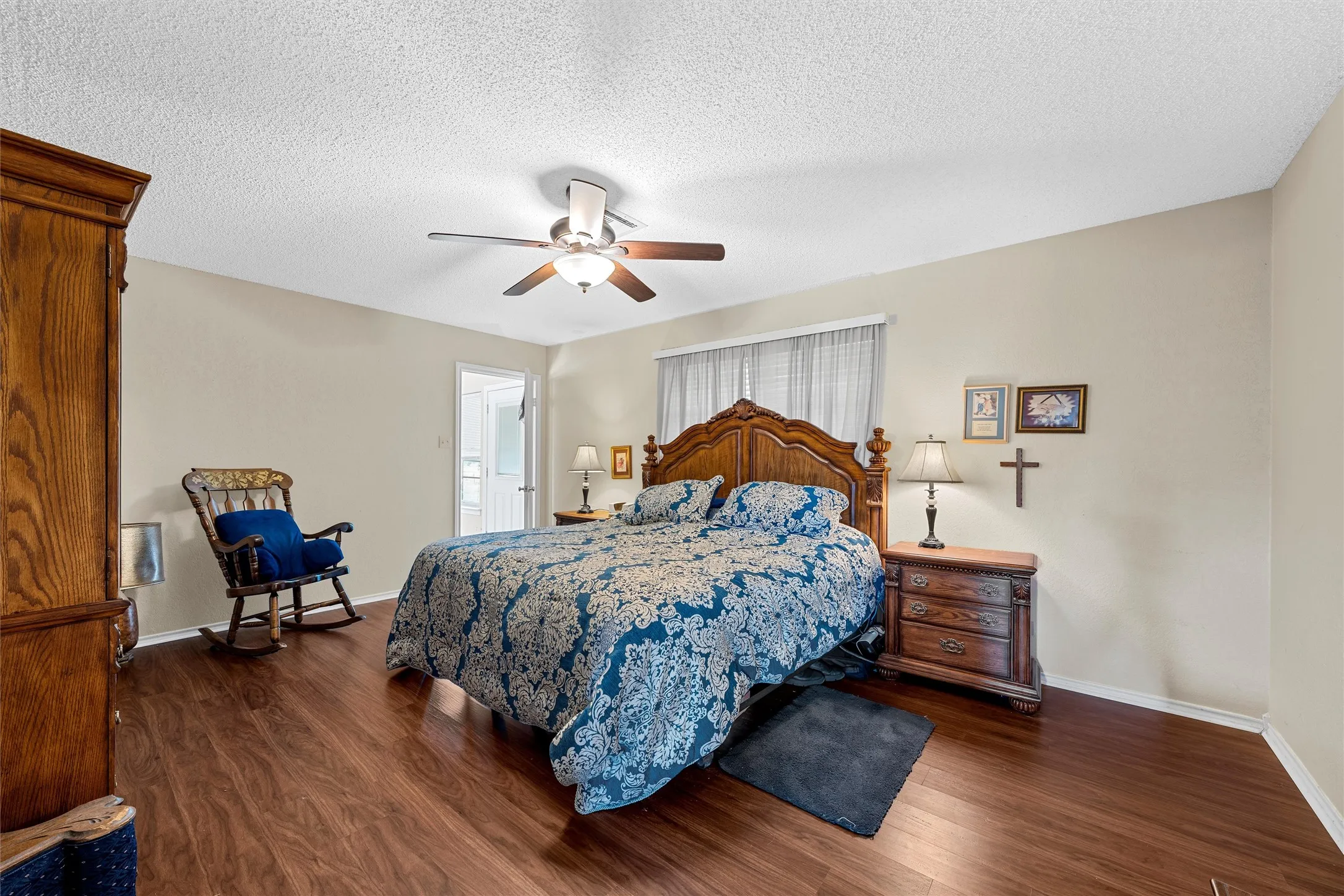 Spacious room featuring wood-finish flooring, light-toned walls, a ceiling fan with integrated lighting, and a window with vertical blinds