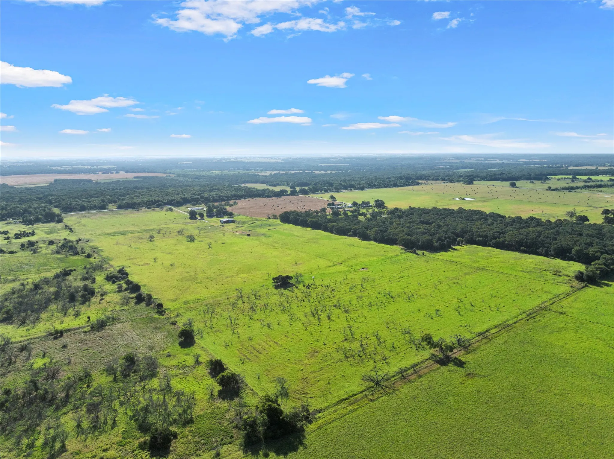 Expansive green acreage featuring open pastures and distant tree lines
