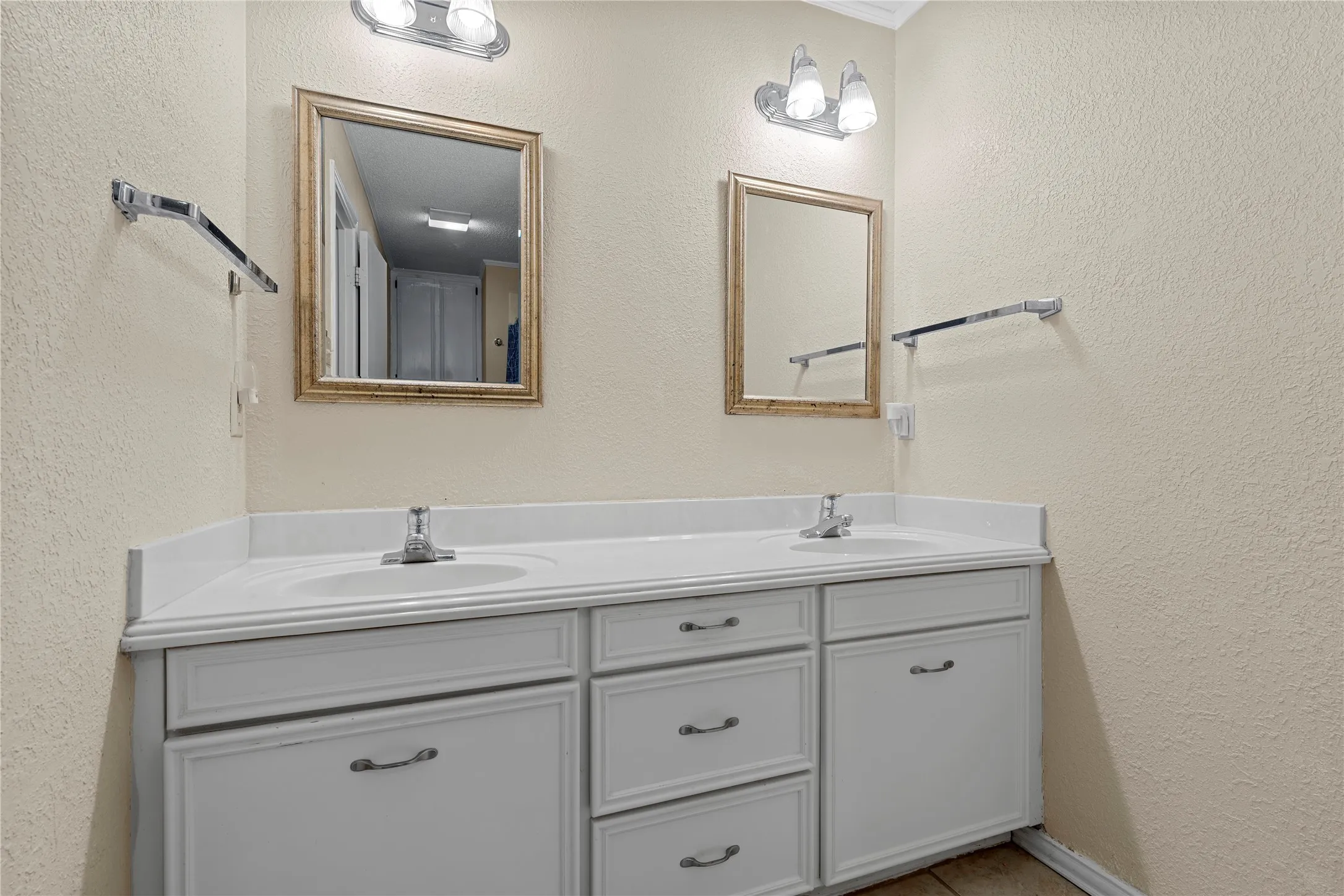 Double vanity with white cabinetry, integrated sinks, chrome faucets, and two framed mirrors
