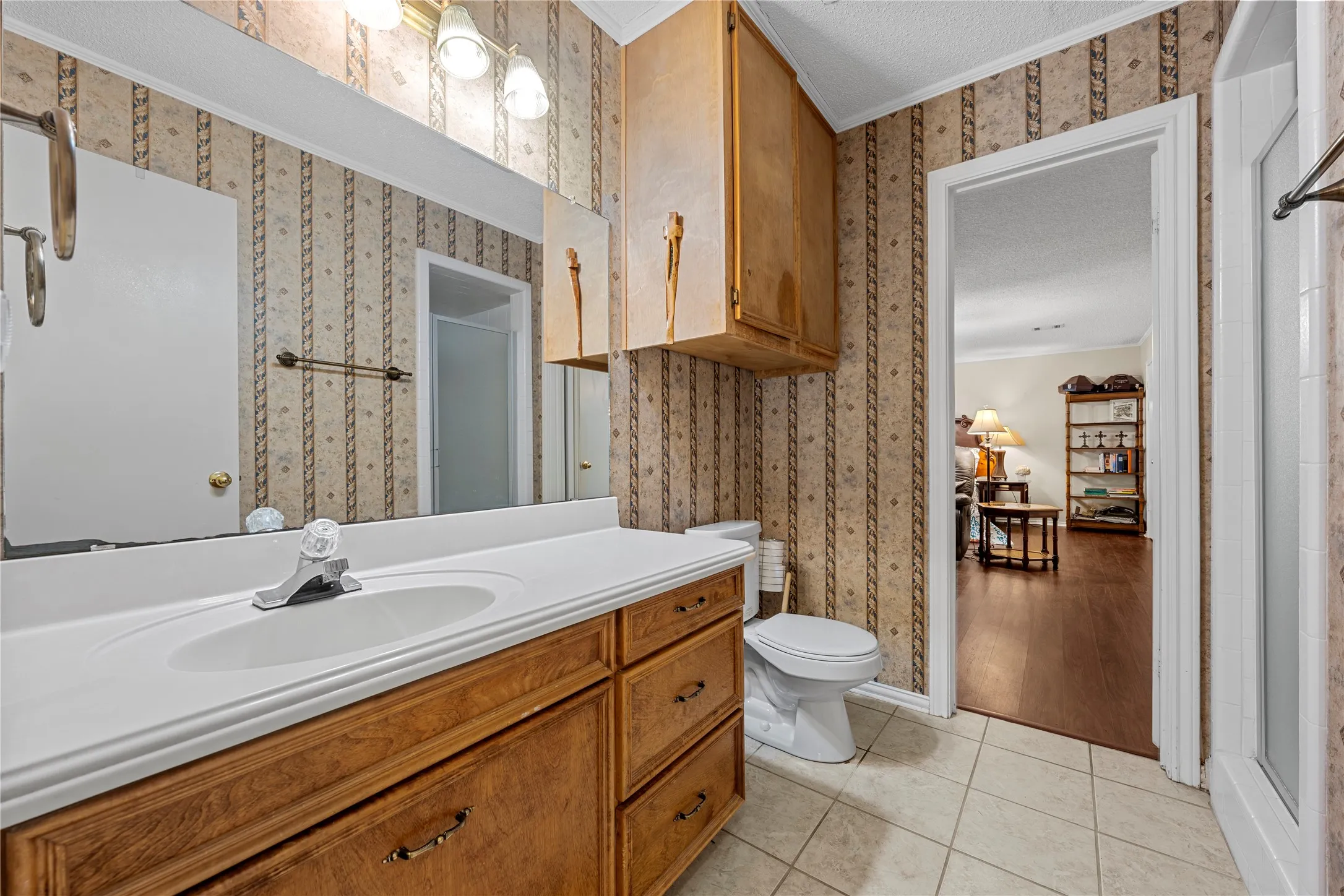 Bathroom featuring a wood-finish vanity with an integrated sink and laminate countertop