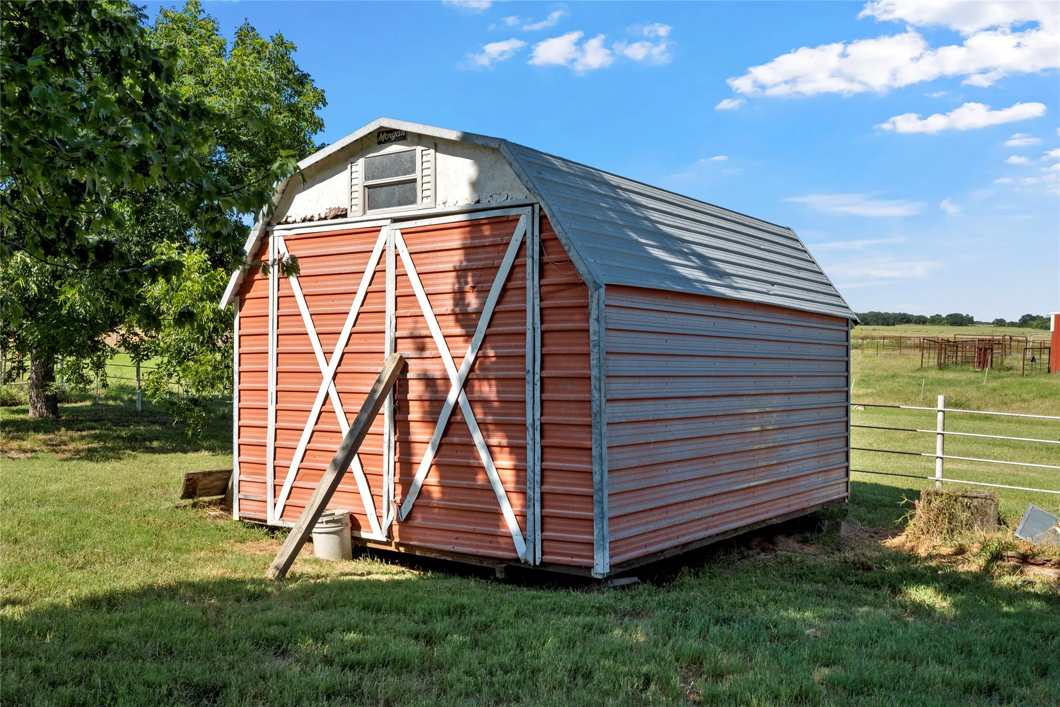 Utility shed featuring a gambrel roof, red siding, and white trim