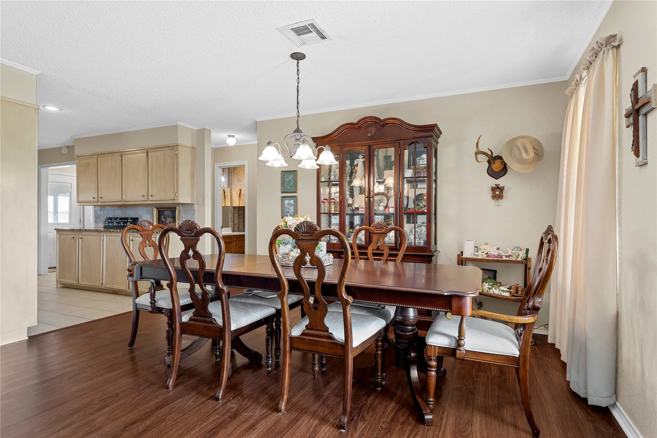 Spacious dining area featuring wood-finish flooring, a contemporary chandelier, and direct access to the kitchen