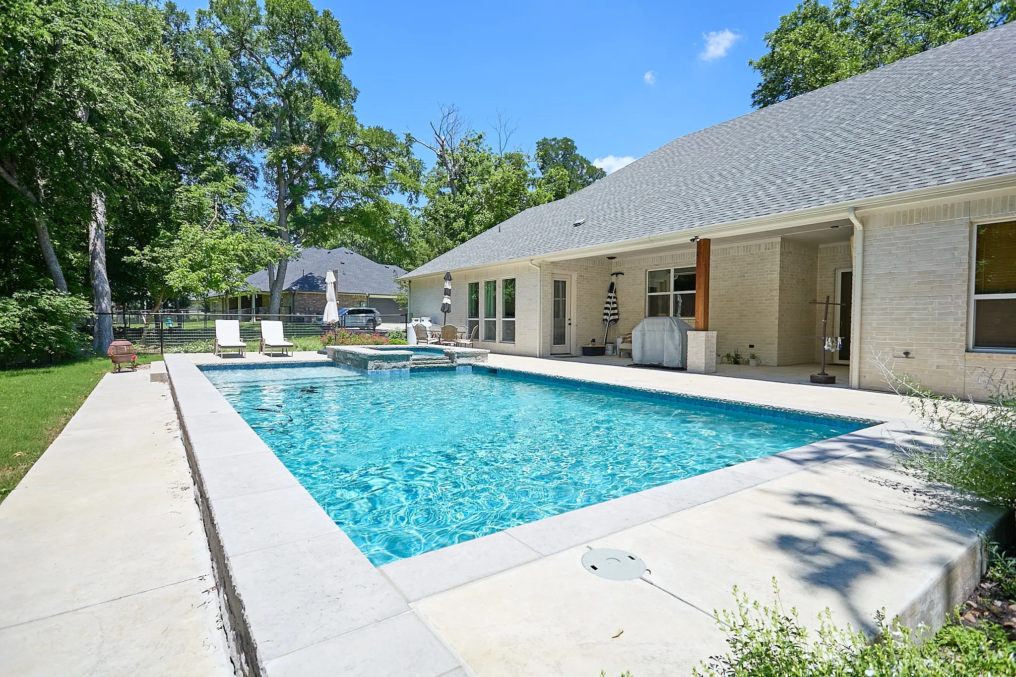 Rectangular swimming pool with integrated spa and waterfall feature