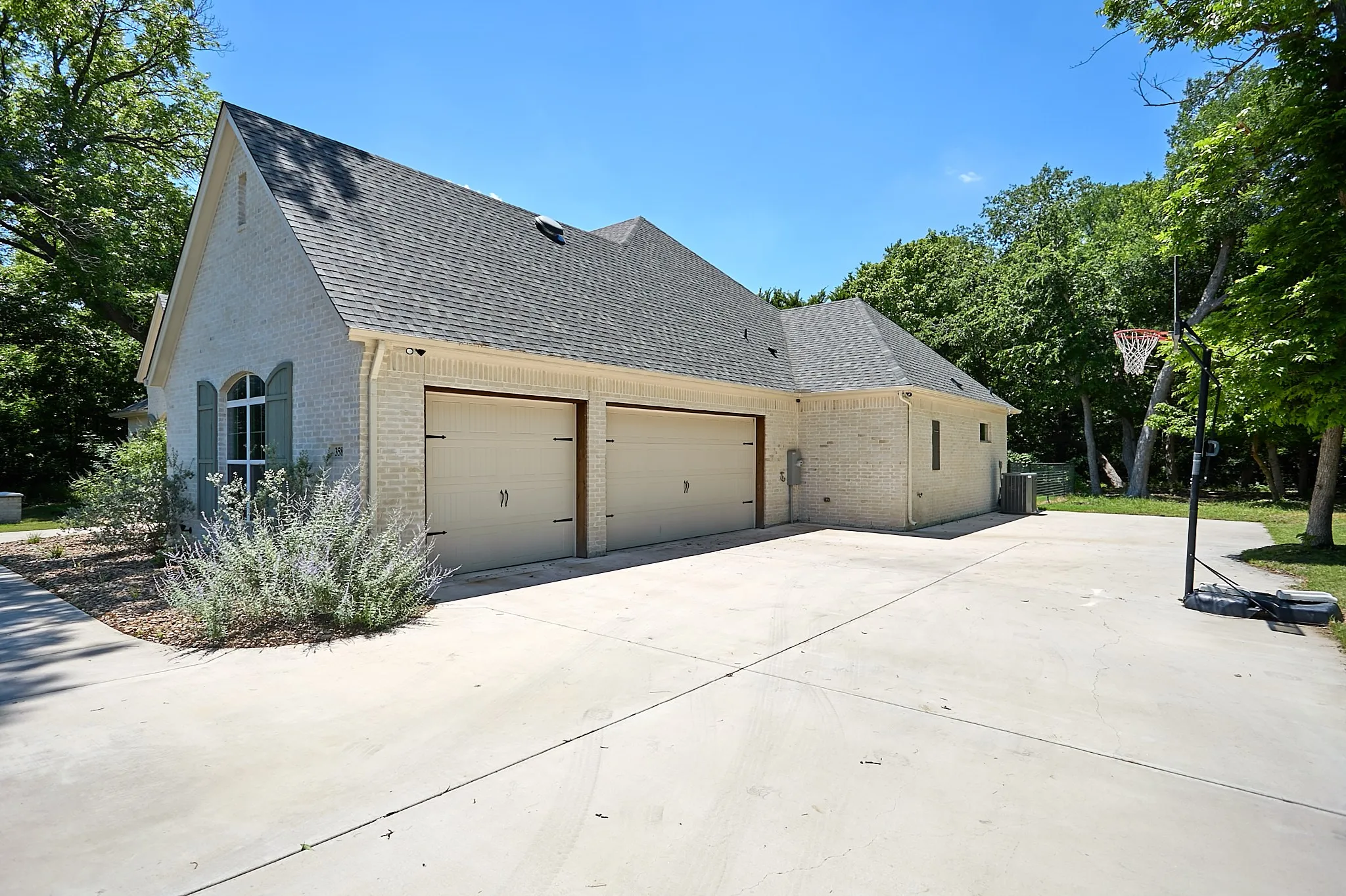 Light-colored brick exterior featuring a two-car garage with carriage-style doors