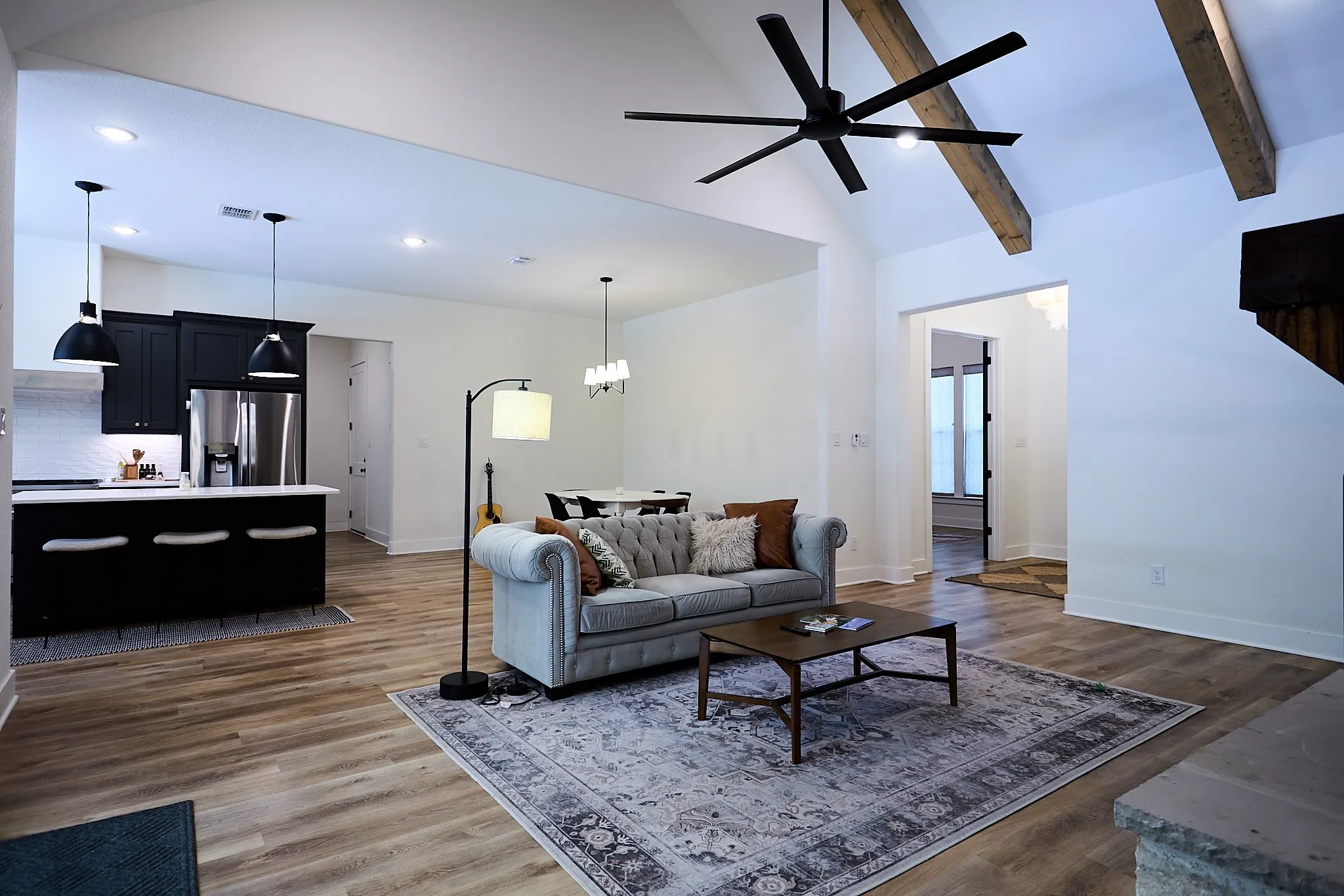 Open-concept living area featuring vaulted ceilings with exposed wood beams