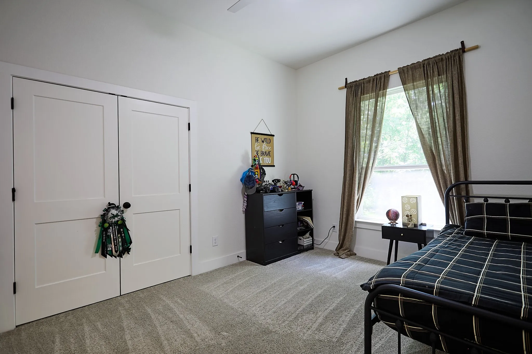 White two-panel bi-fold doors, white baseboards, light grey carpeting, and a window with natural light