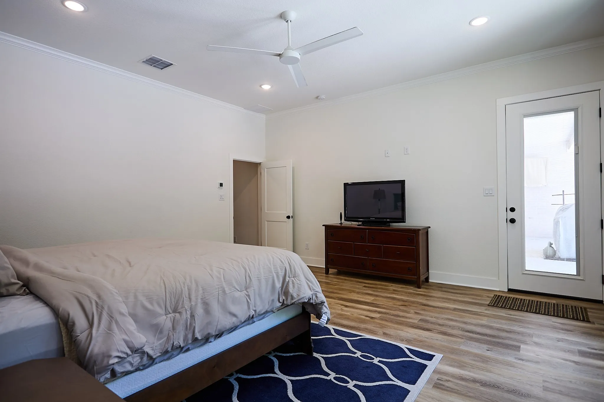Spacious room featuring wood-finish flooring, a ceiling fan, recessed lighting, and crown molding