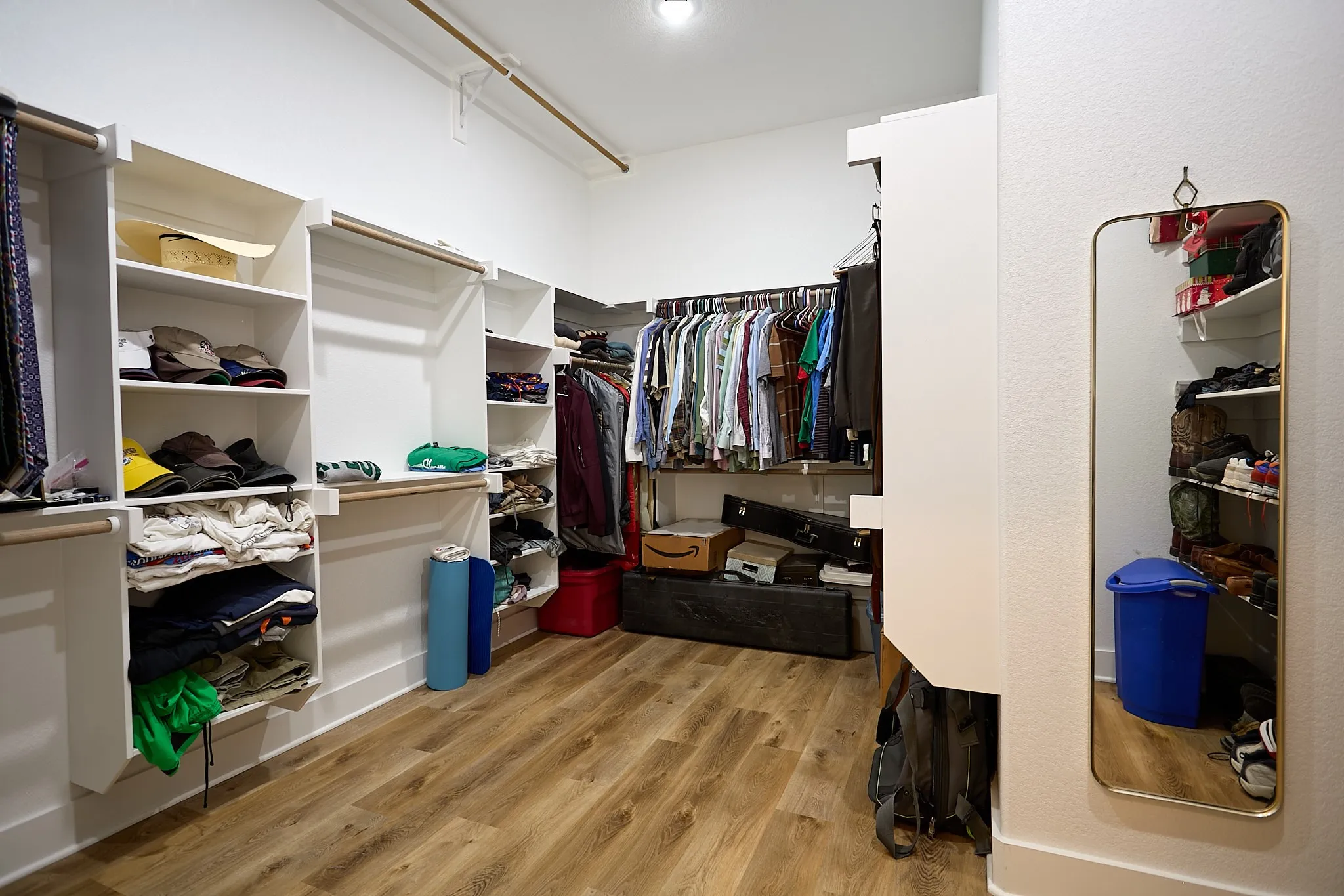 Custom-designed closet system featuring extensive shelving, hanging rods, and wood-finish flooring