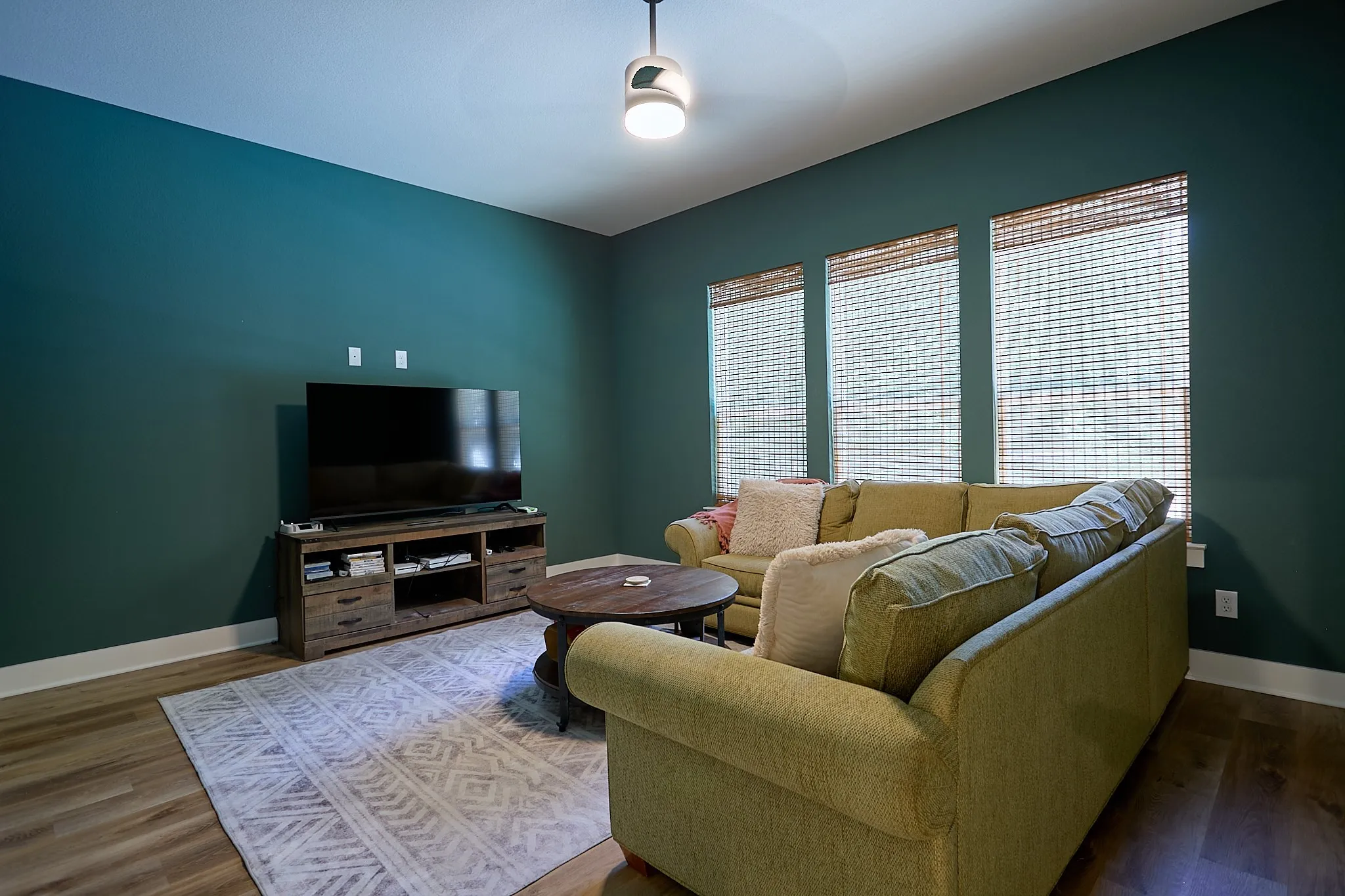 Spacious interior room featuring rich teal walls and wood-finish flooring