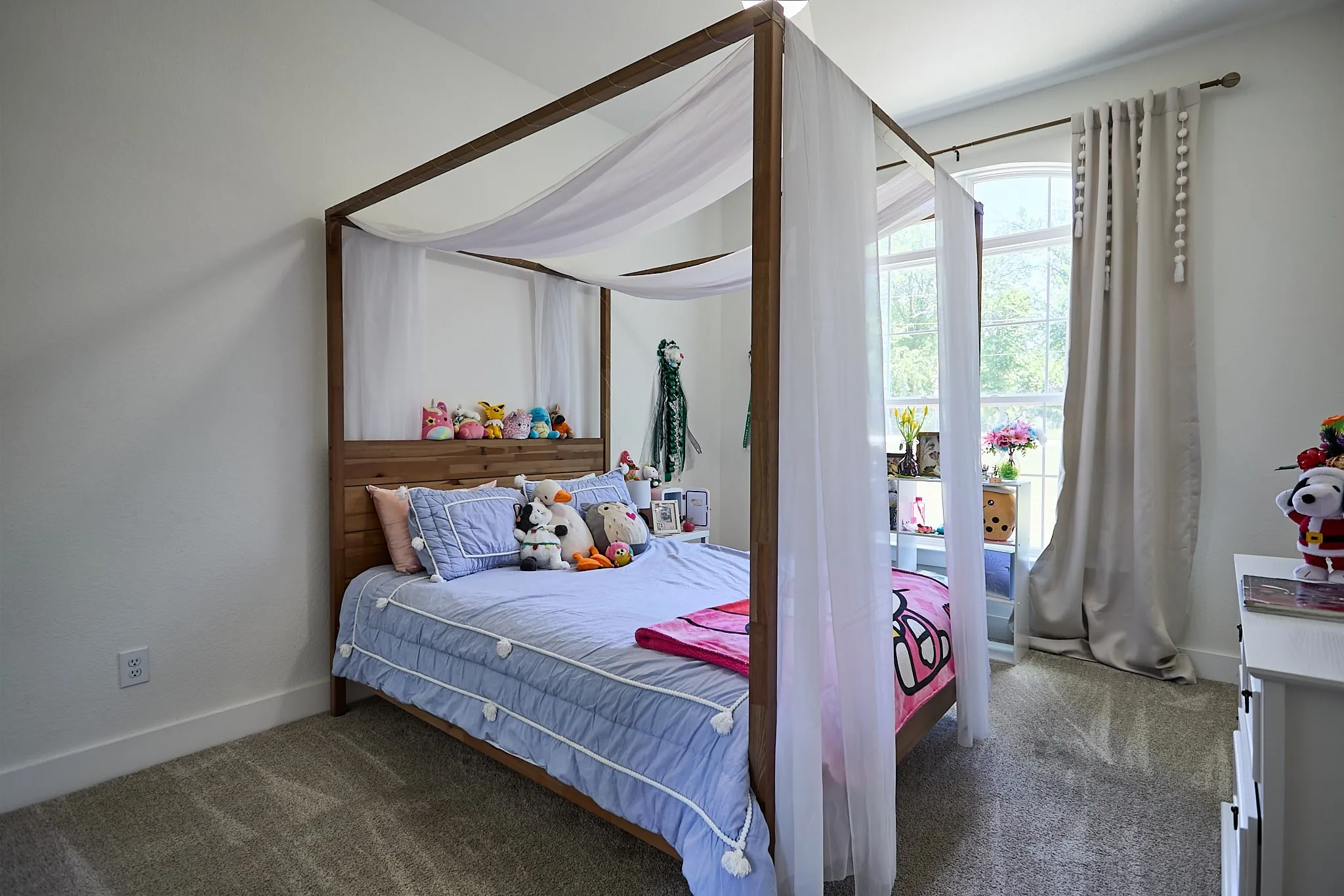 Carpeted room featuring a tall, vaulted ceiling and a canopy bed frame