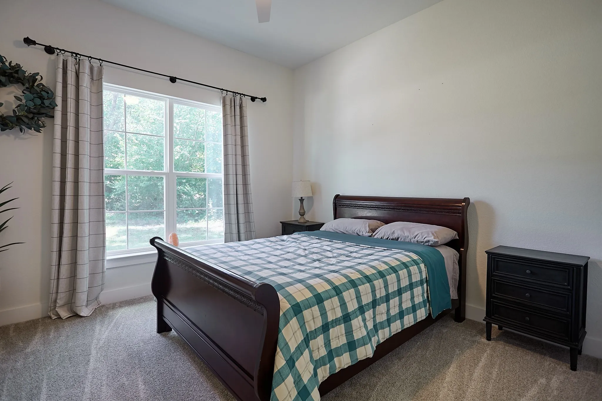Spacious room featuring light gray carpeting, a large window offering natural light, and neutral wall tones