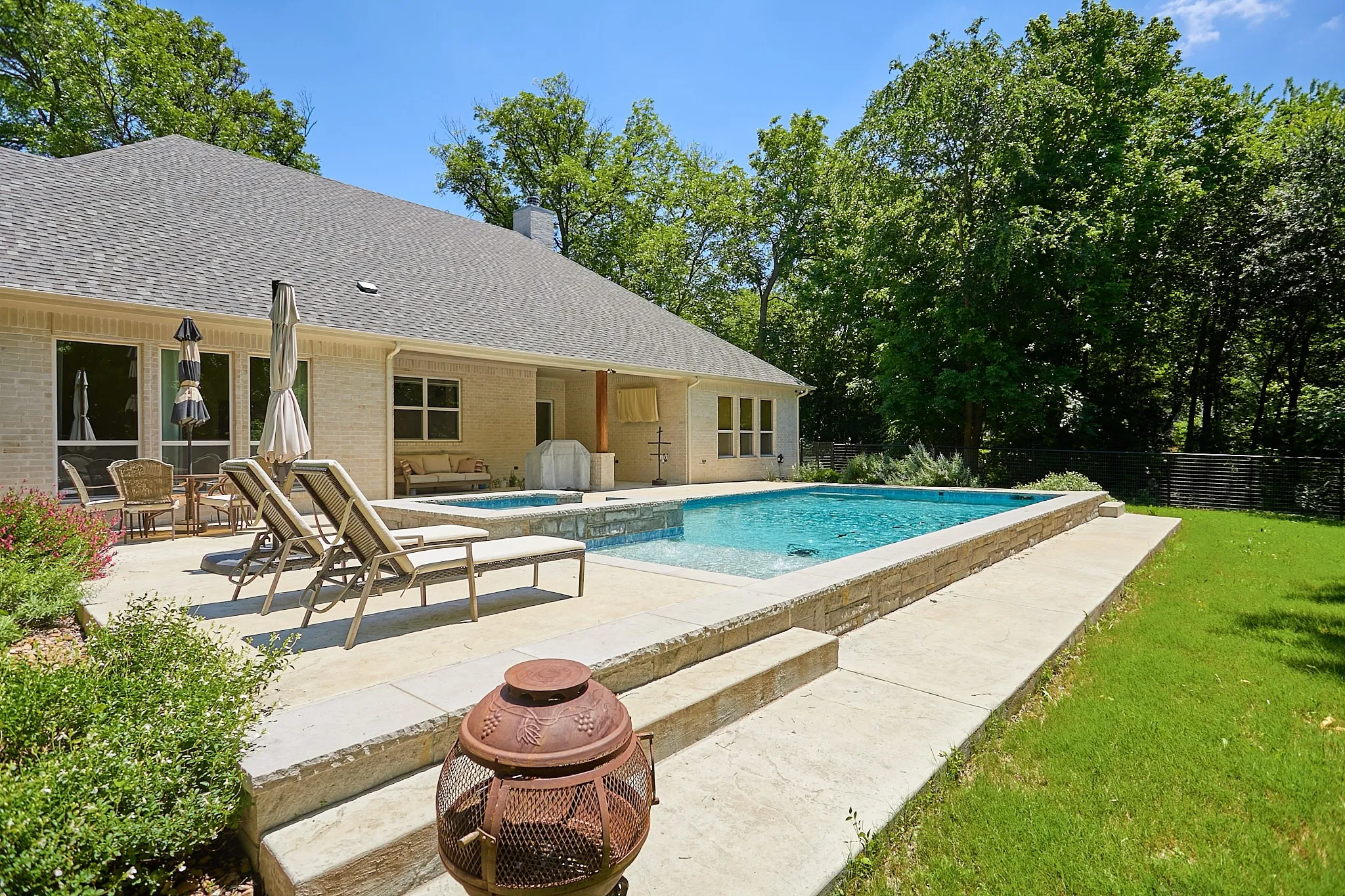Spacious outdoor living area featuring a rectangular pool and integrated spa