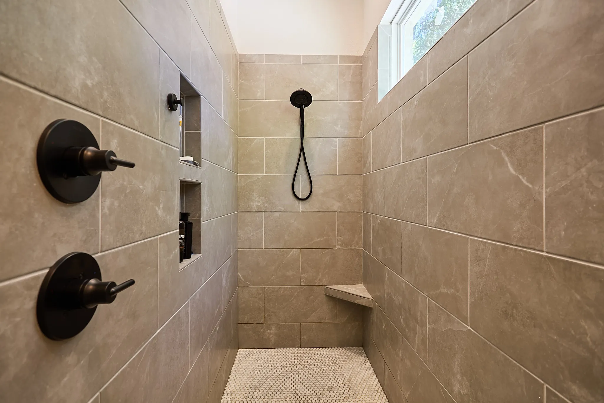 Tile shower with matte black fixtures and a built-in bench