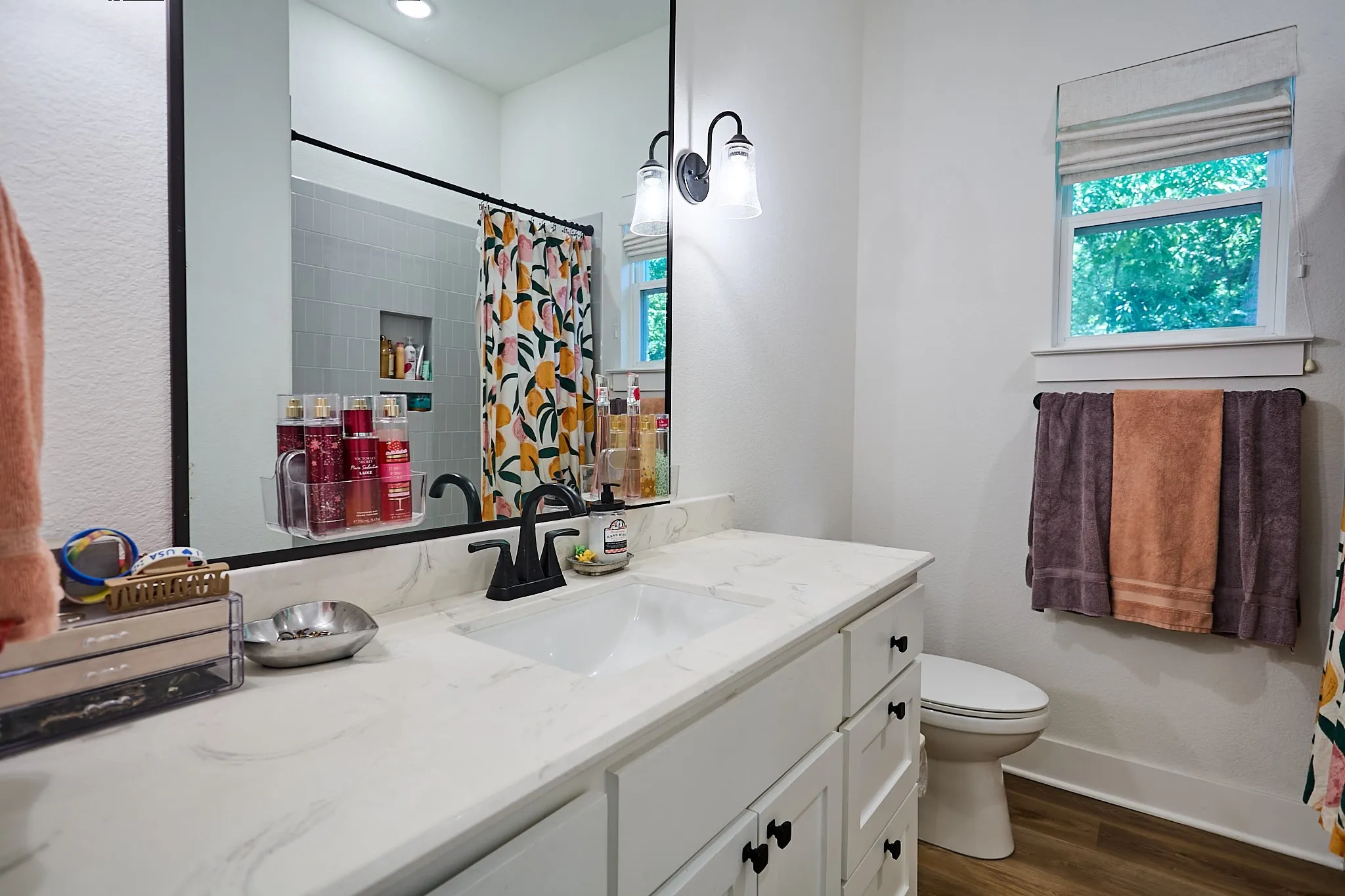 Bathroom vanity with a single basin, stone-finish countertop, and black hardware