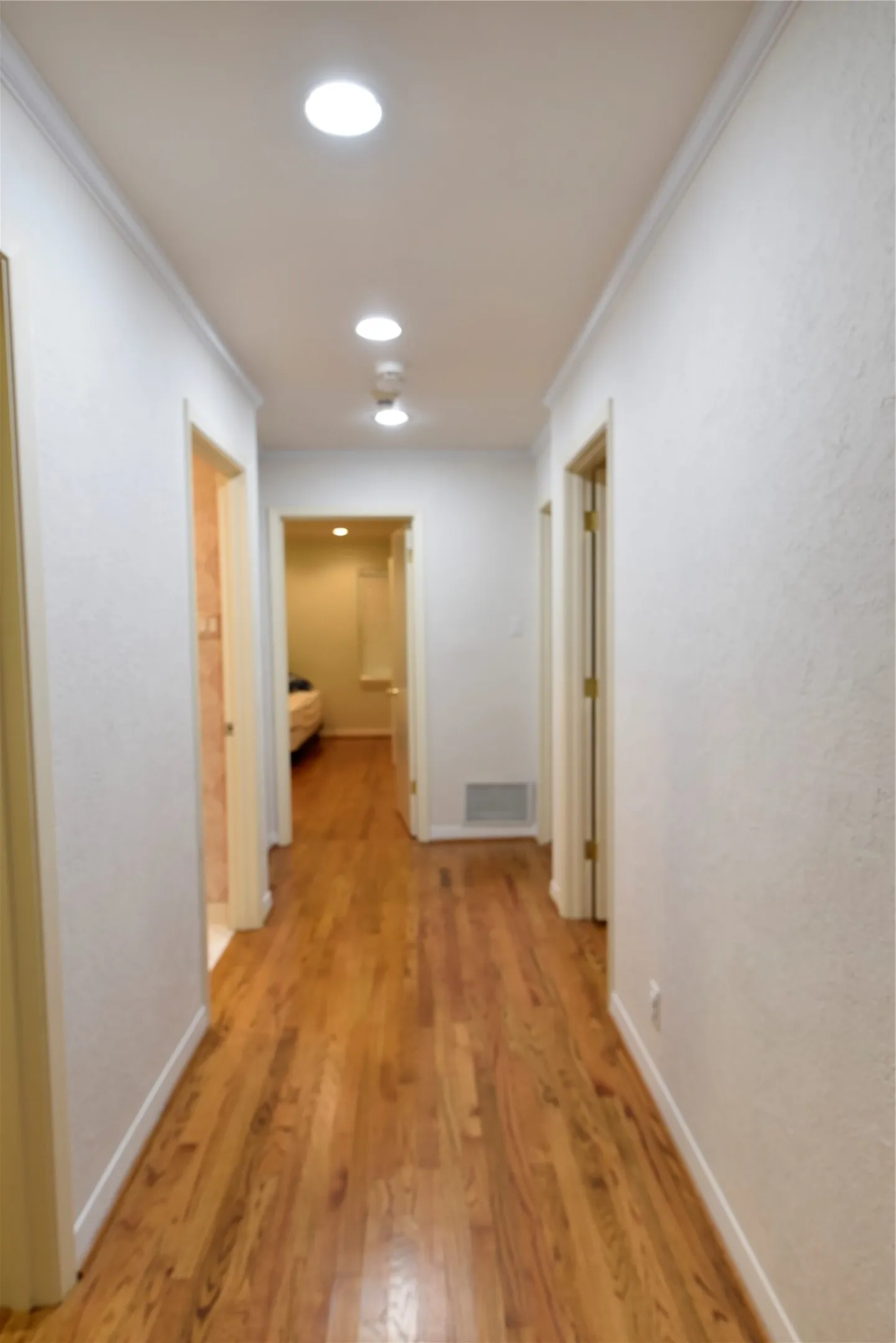 Hallway featuring wood-finish flooring, white painted walls, and recessed ceiling lighting