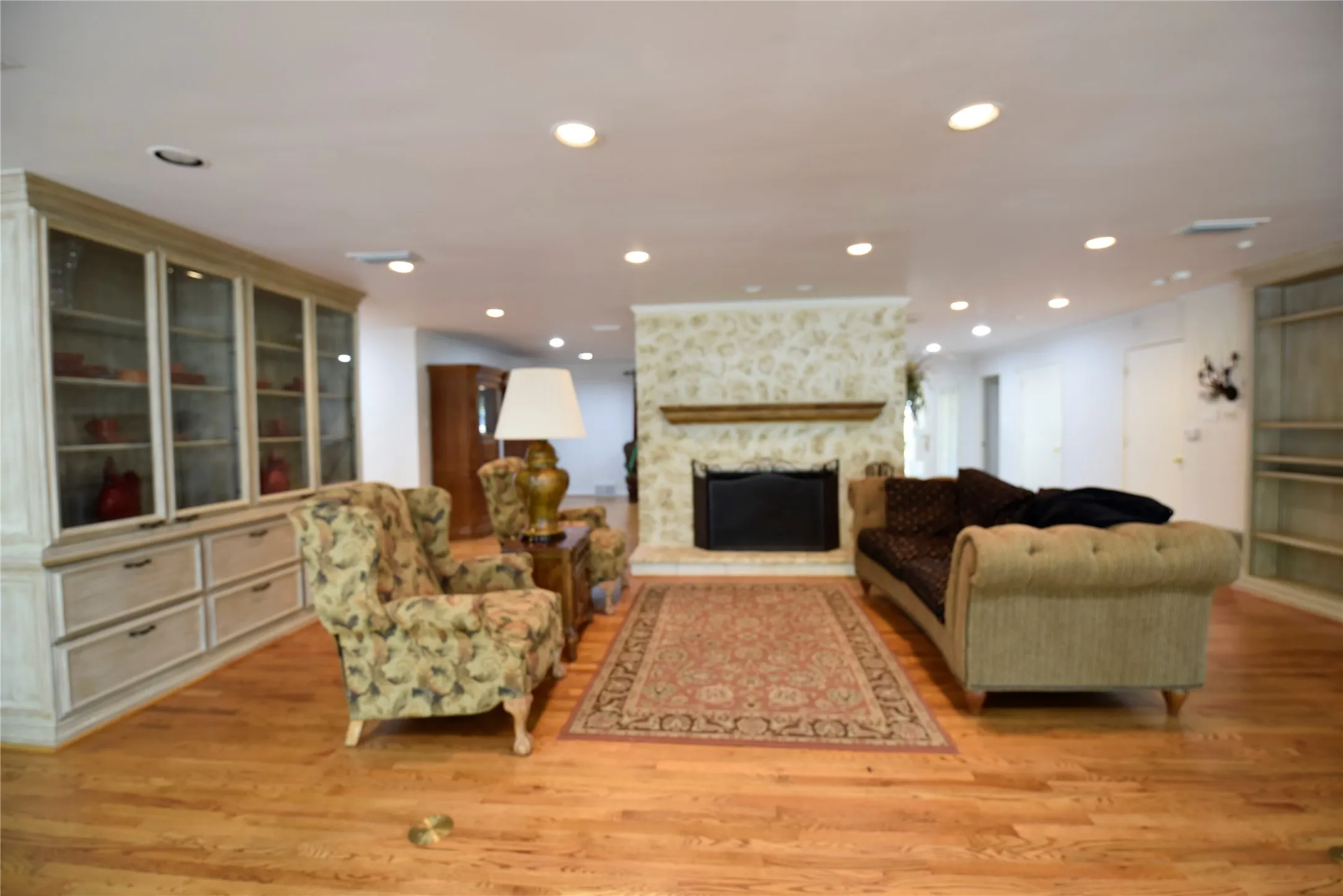 Spacious room featuring wood-finish flooring and recessed lighting