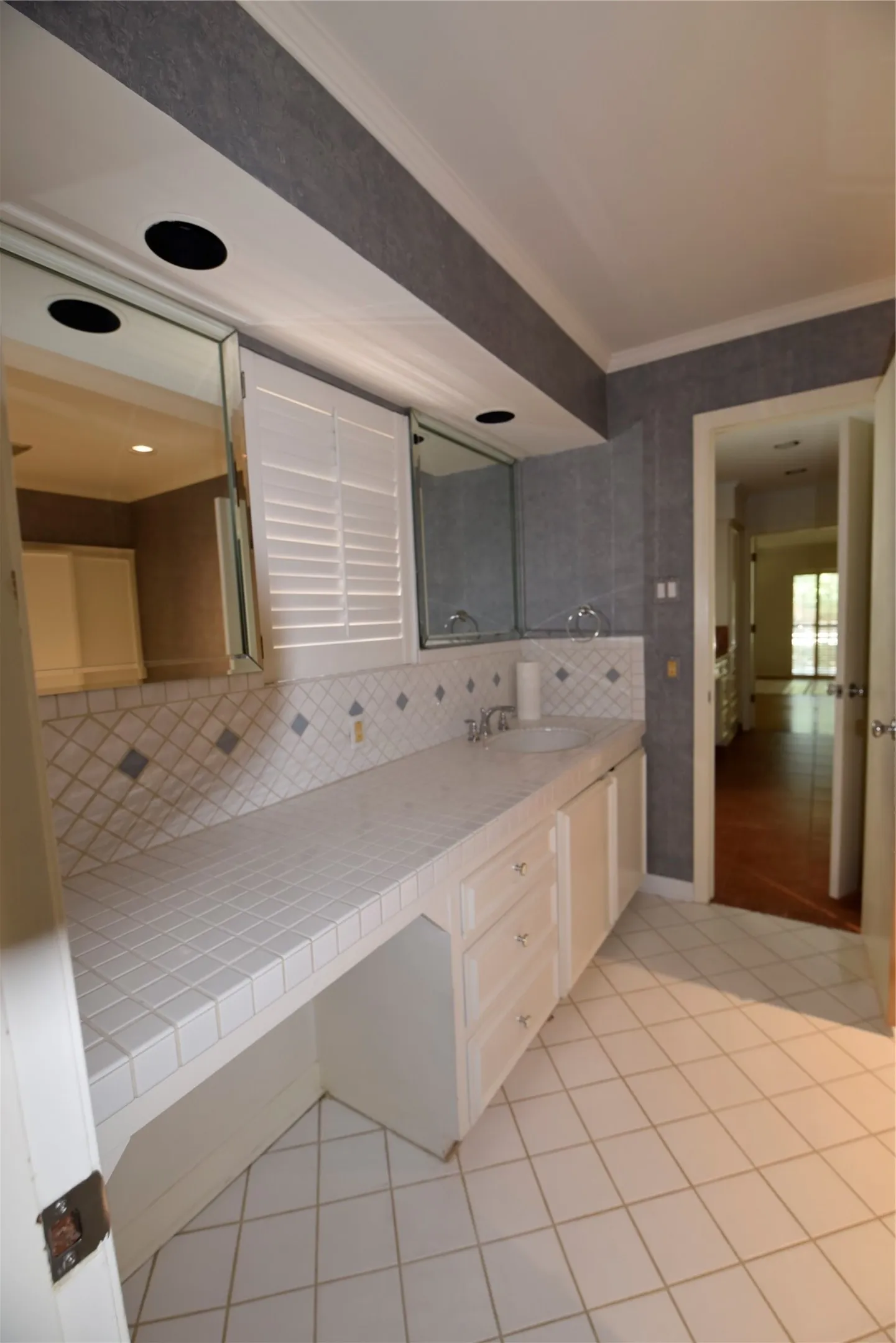 Bathroom vanity featuring a tiled countertop, integrated sink, and white cabinetry with drawers