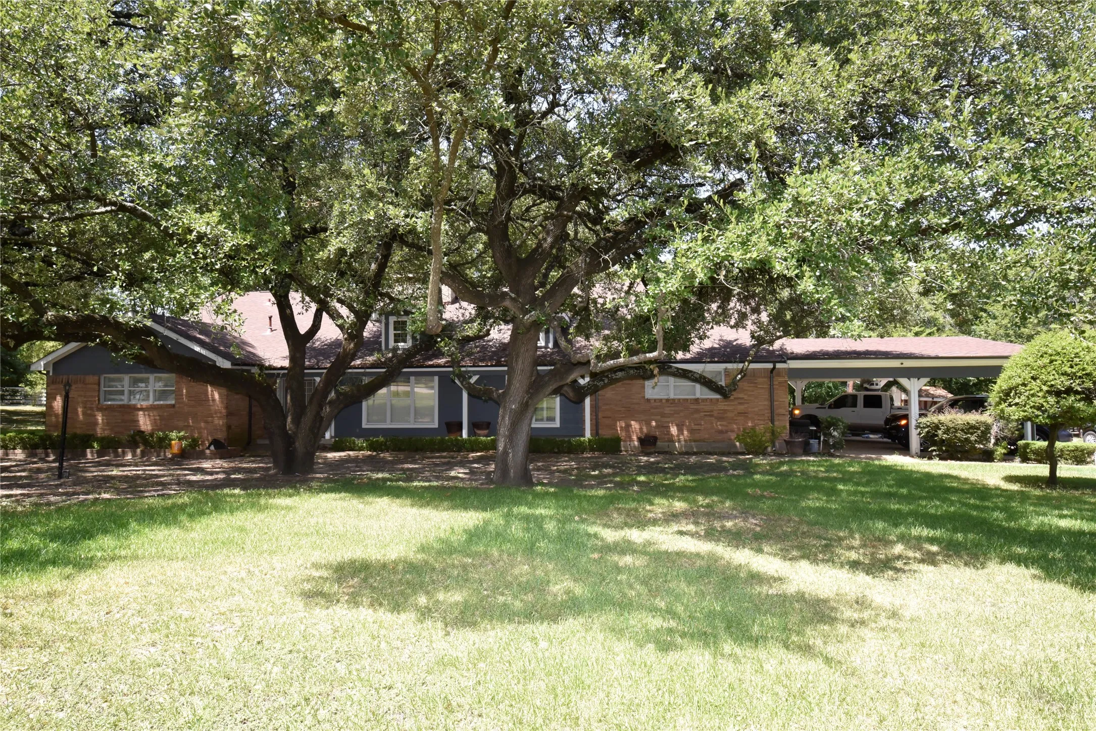 Ranch-style residence featuring a brick and blue siding exterior, a red-toned shingle roof, and a covered carport