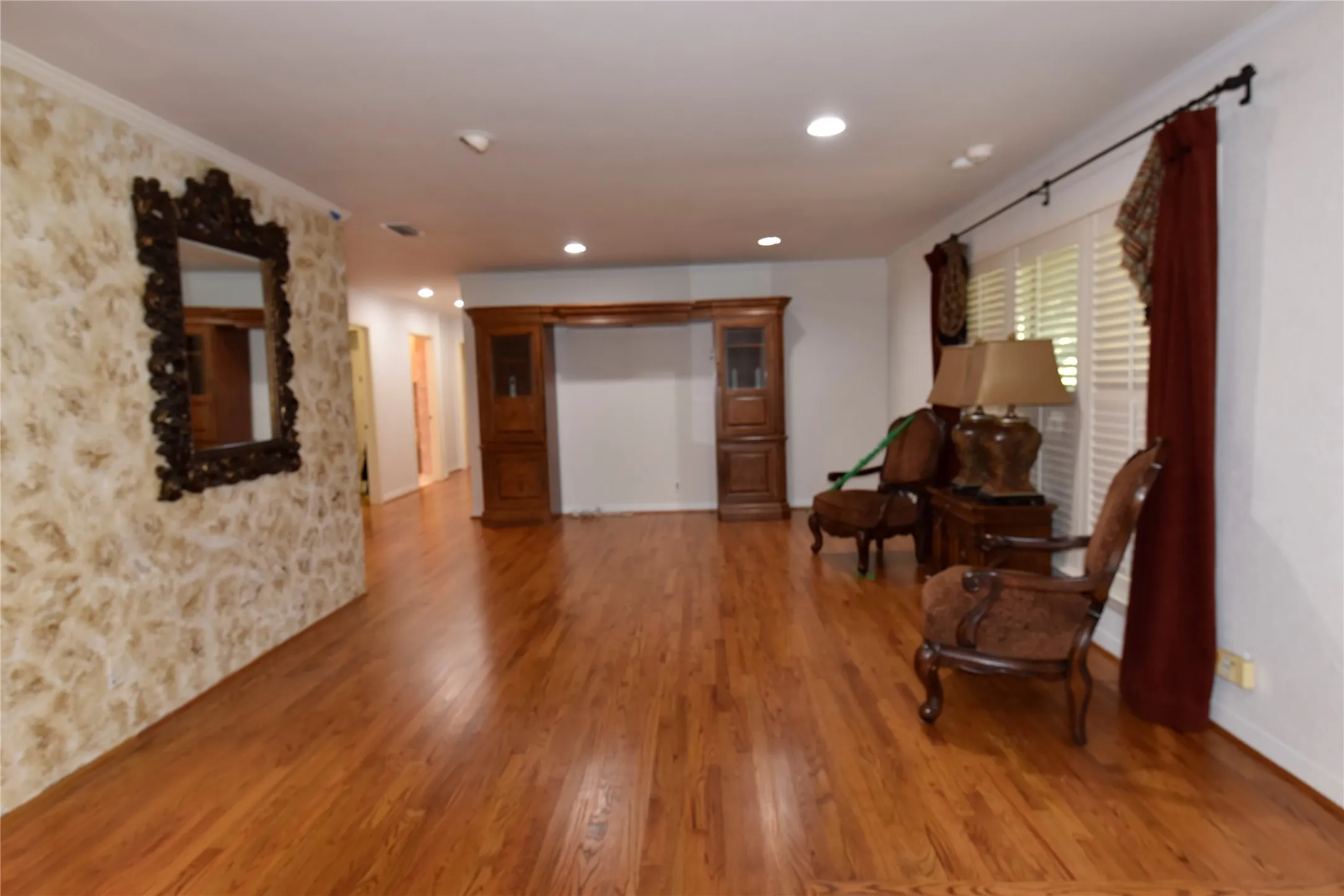 Spacious room featuring wood-finish flooring, recessed lighting, and a prominent built-in wood cabinet