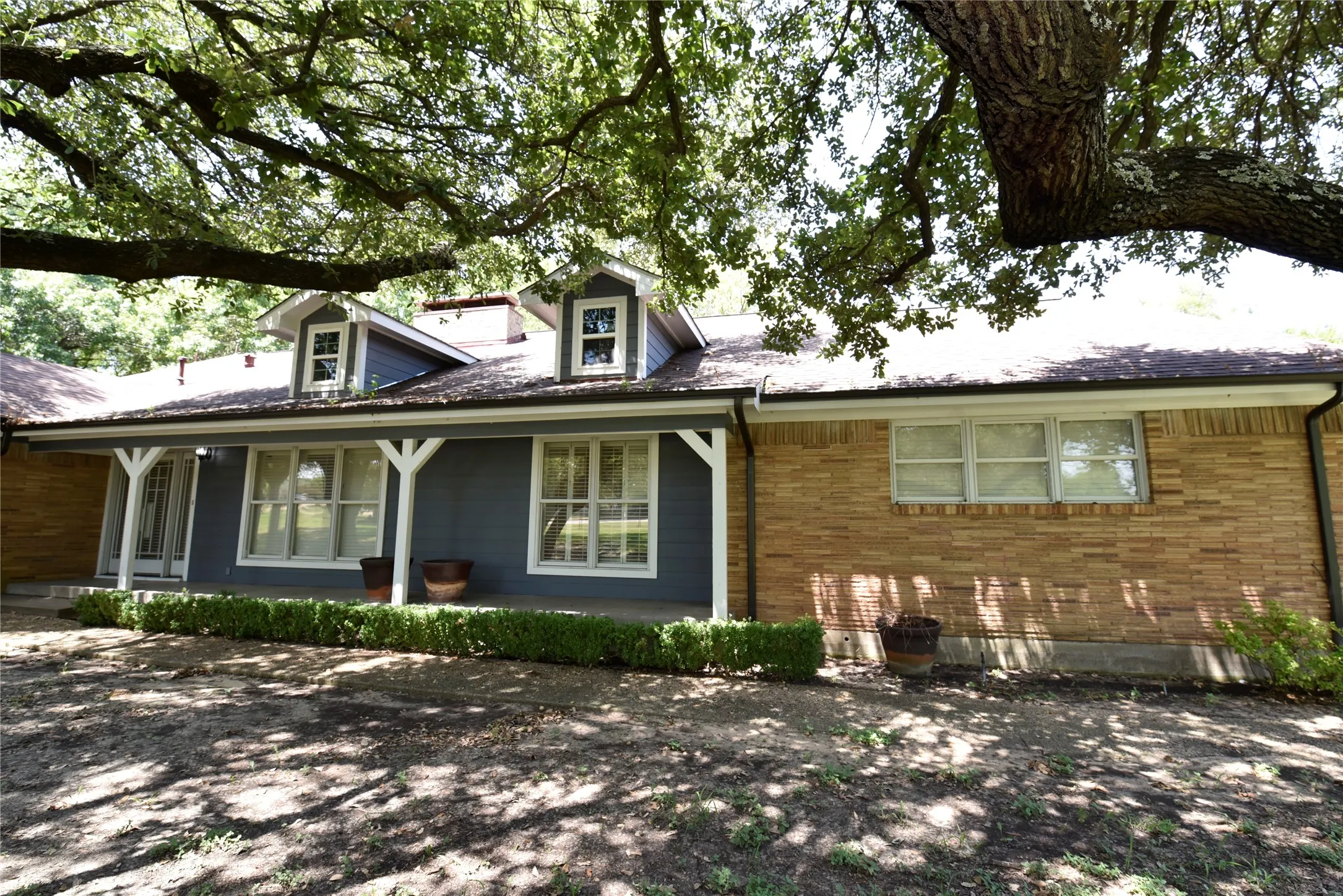 Exterior featuring a combination of brick and blue siding, white trim, and a covered front porch with white columns