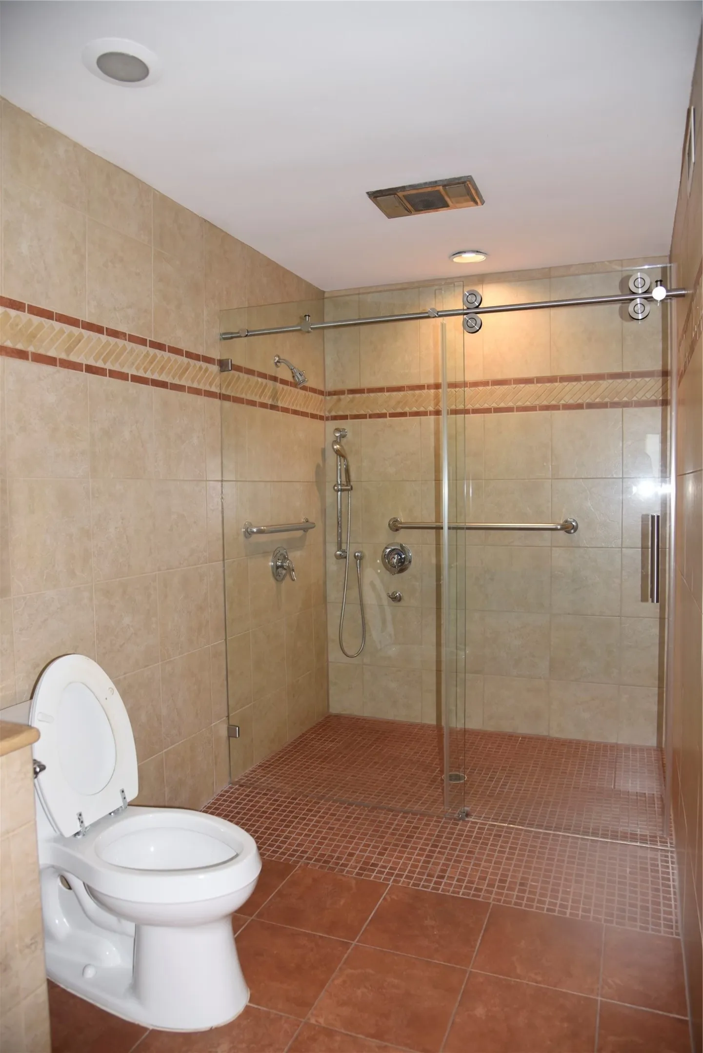 Walk-in shower with clear glass sliding doors and full wall tiling