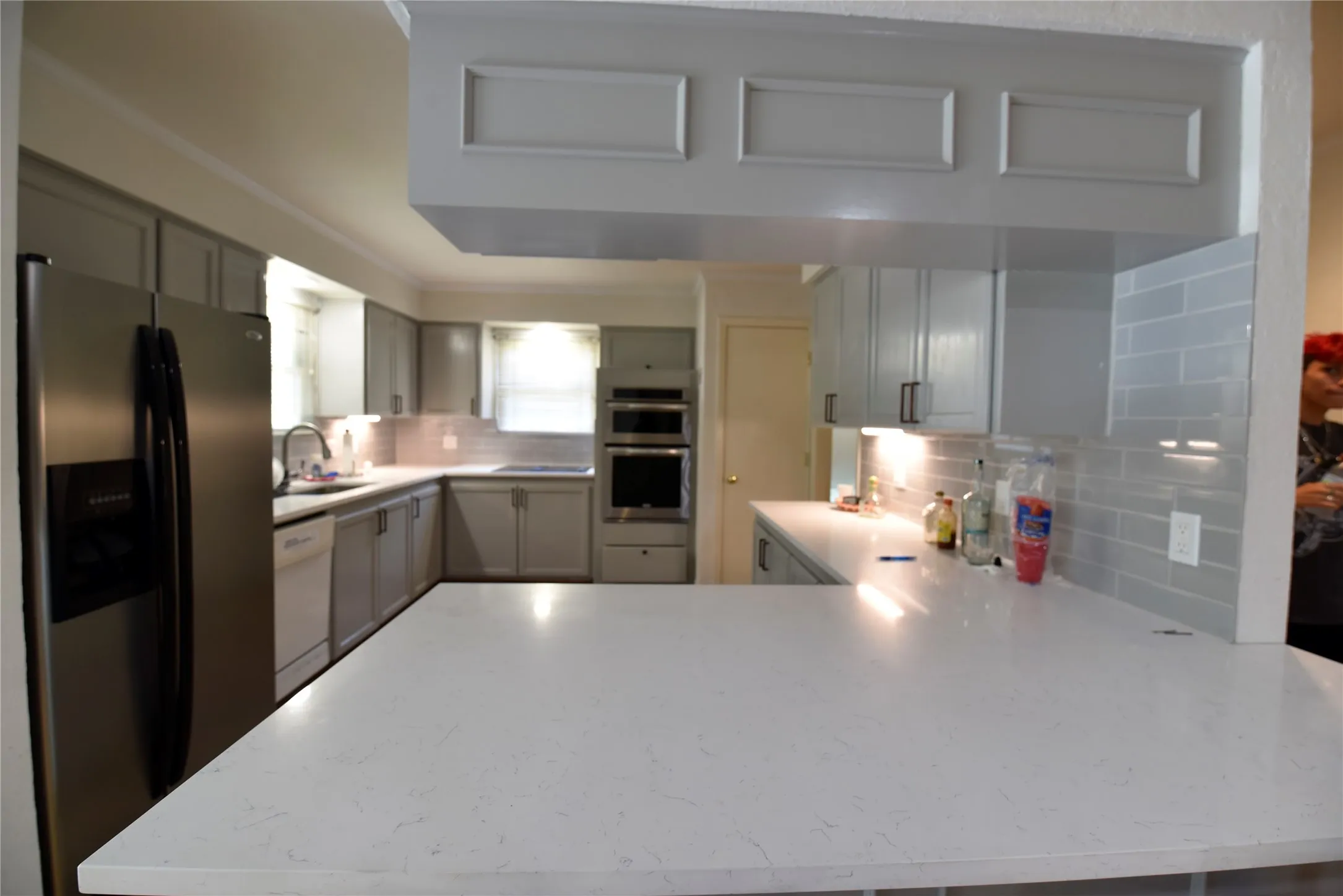 Expansive kitchen island featuring a light-toned countertop, complemented by light grey cabinetry with dark hardware