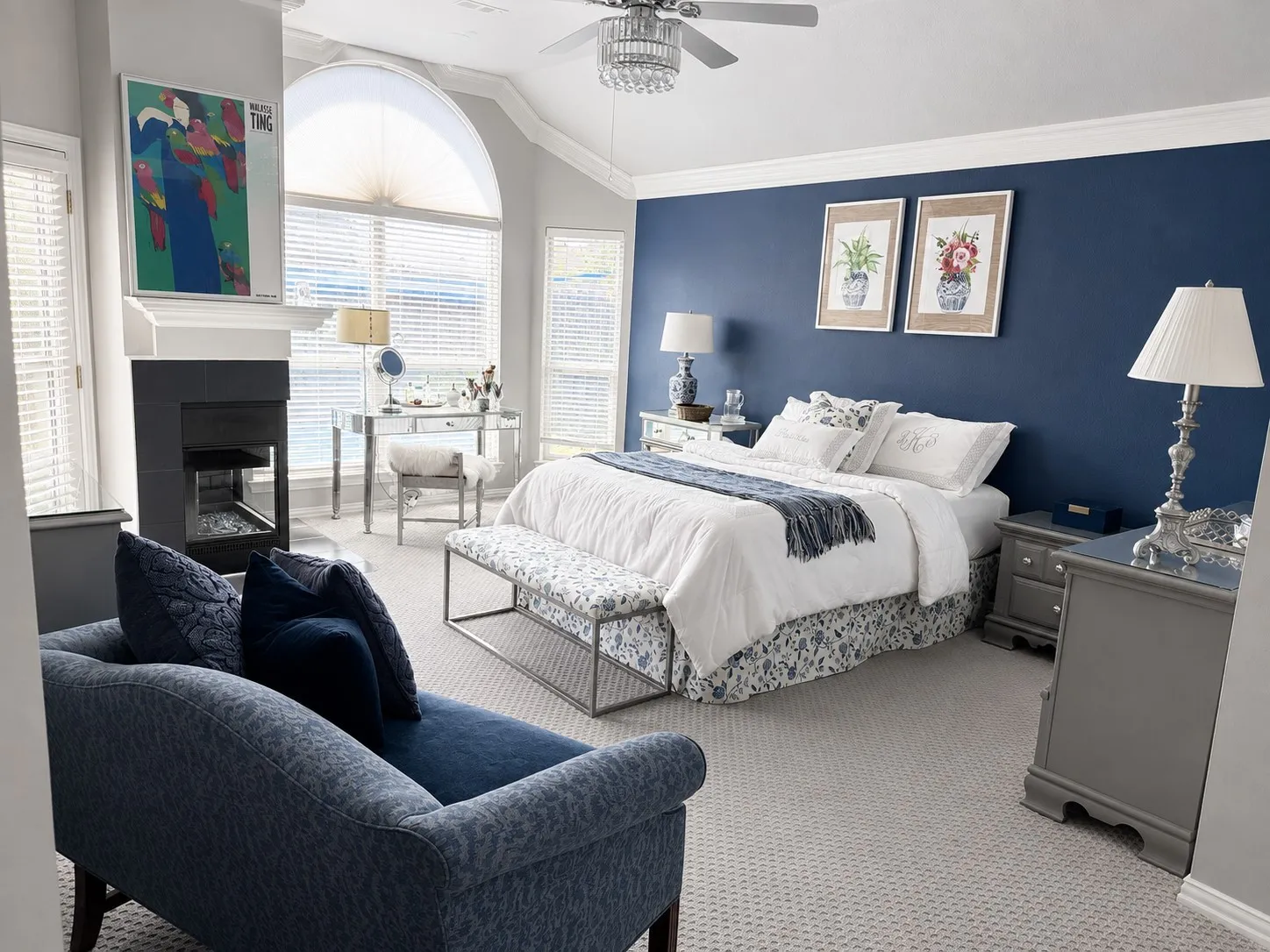 Arched window with blinds, fireplace with dark tile surround, light neutral carpeting, vaulted ceiling, and crown molding