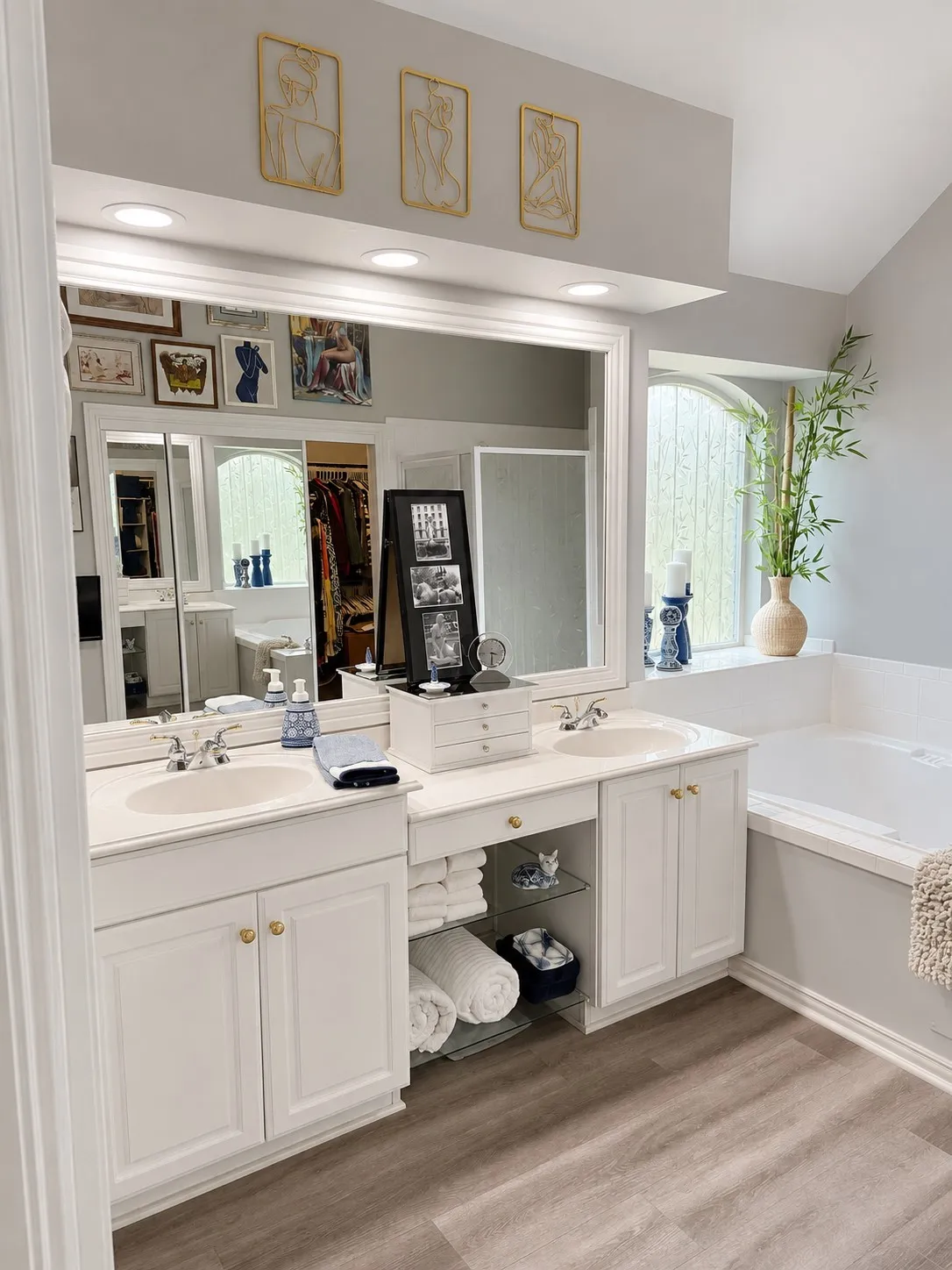 Dual vanity with white cabinetry, ample counter space, built-in storage, and wood-finish flooring