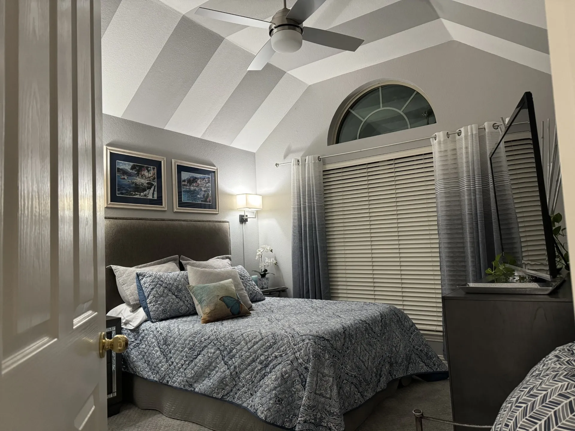 Bedroom with vaulted ceiling featuring bold geometric stripe detailing and ceiling fan