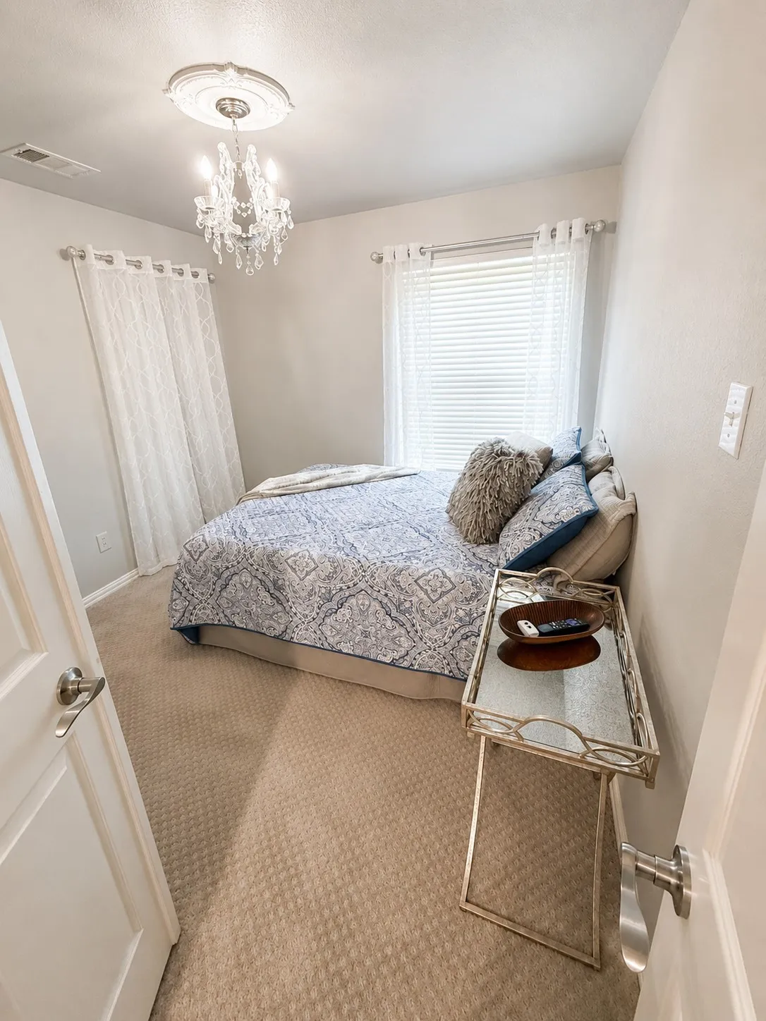 Recessed lighting and ceiling-mounted chandelier illuminate the room