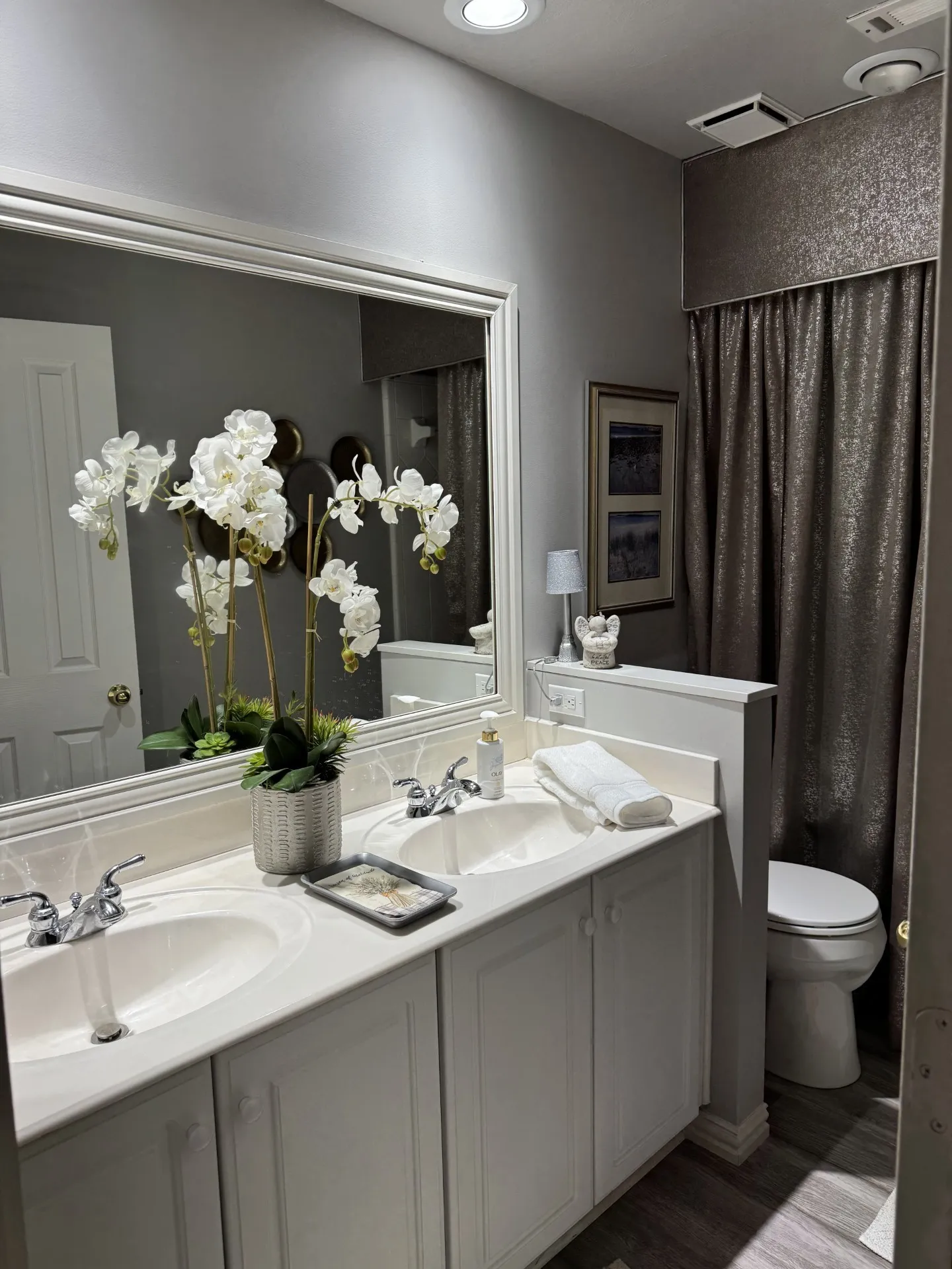 Double vanity with integrated sinks, white cabinetry, and a framed mirror