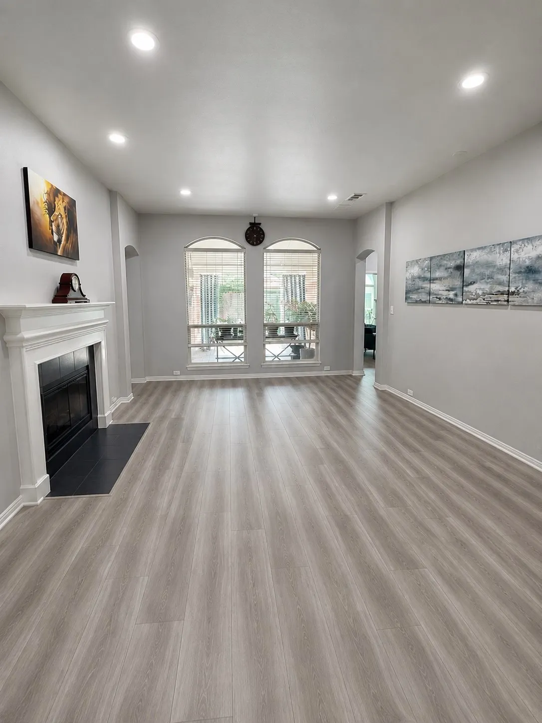 Recessed ceiling lighting, wood-finish flooring, white mantel, black fireplace insert, and arched window details