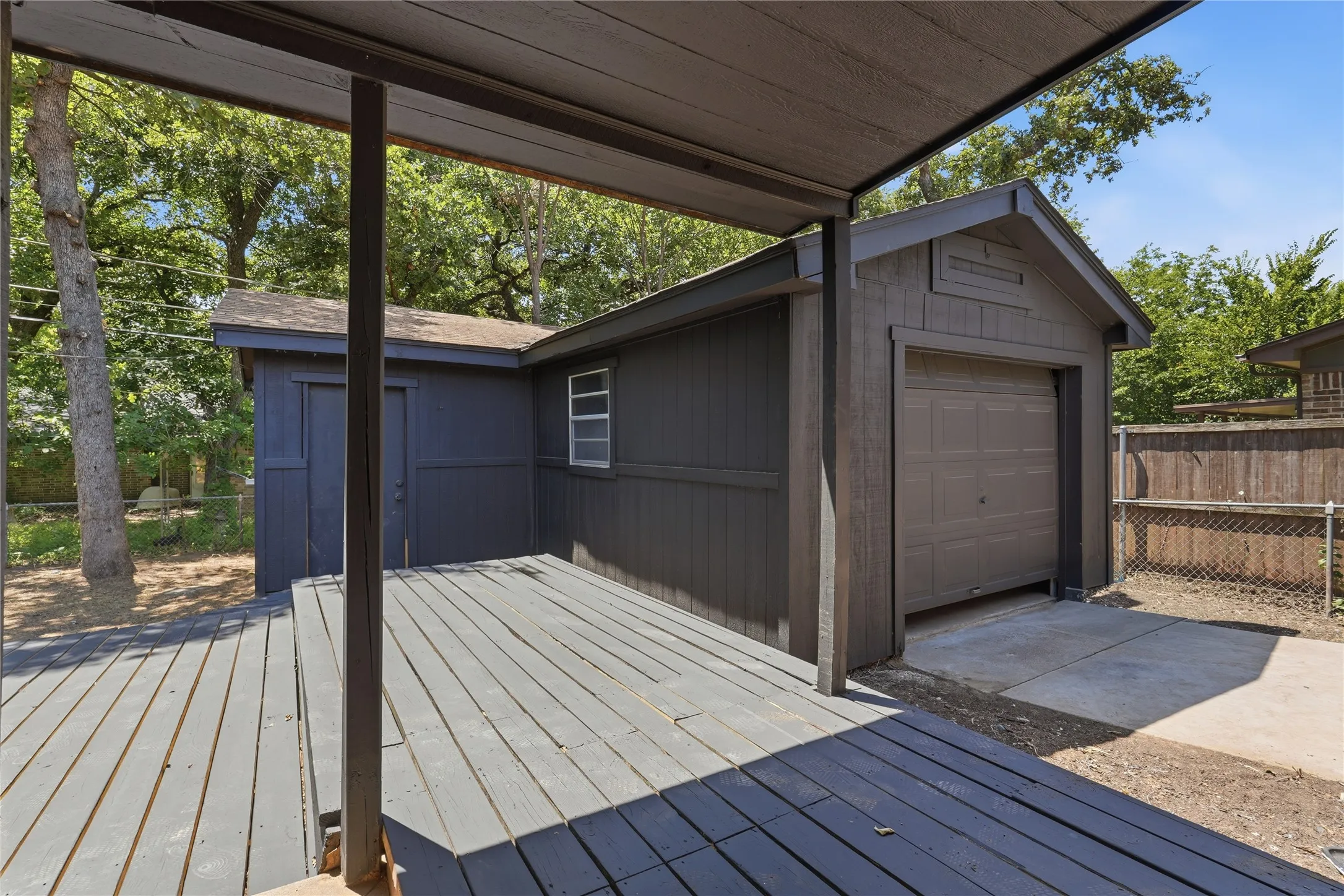 Detached garage structure featuring a brown garage door, a side entry door, and a multi-pane window